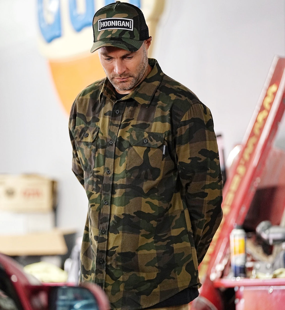 Hoonigan H Icon Camo Woven Flannel Long Sleeve Shirt featuring a camo pattern and Hoonigan logo, displayed on a wooden background.