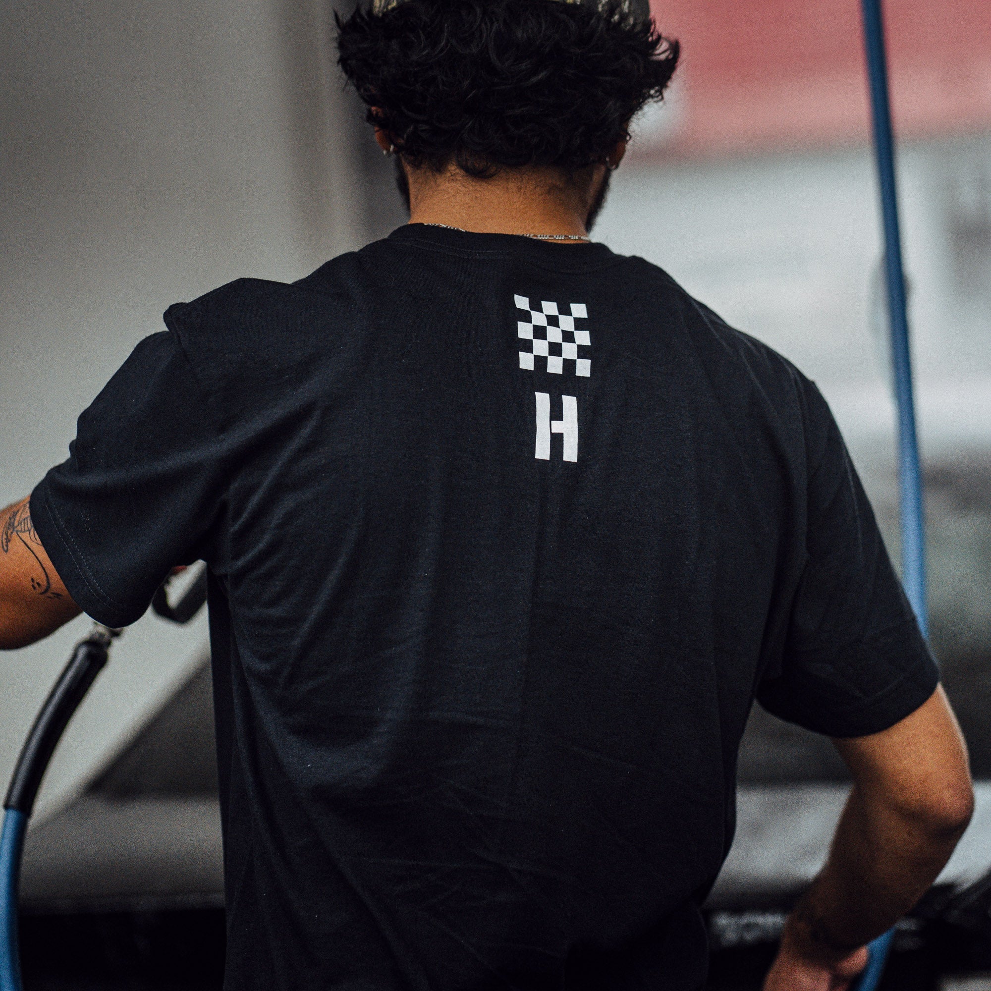 Black Hoonigan AUTOBAHN short sleeve t-shirt featuring a checkered flag design and logo on the back, ideal for motorsport fans.