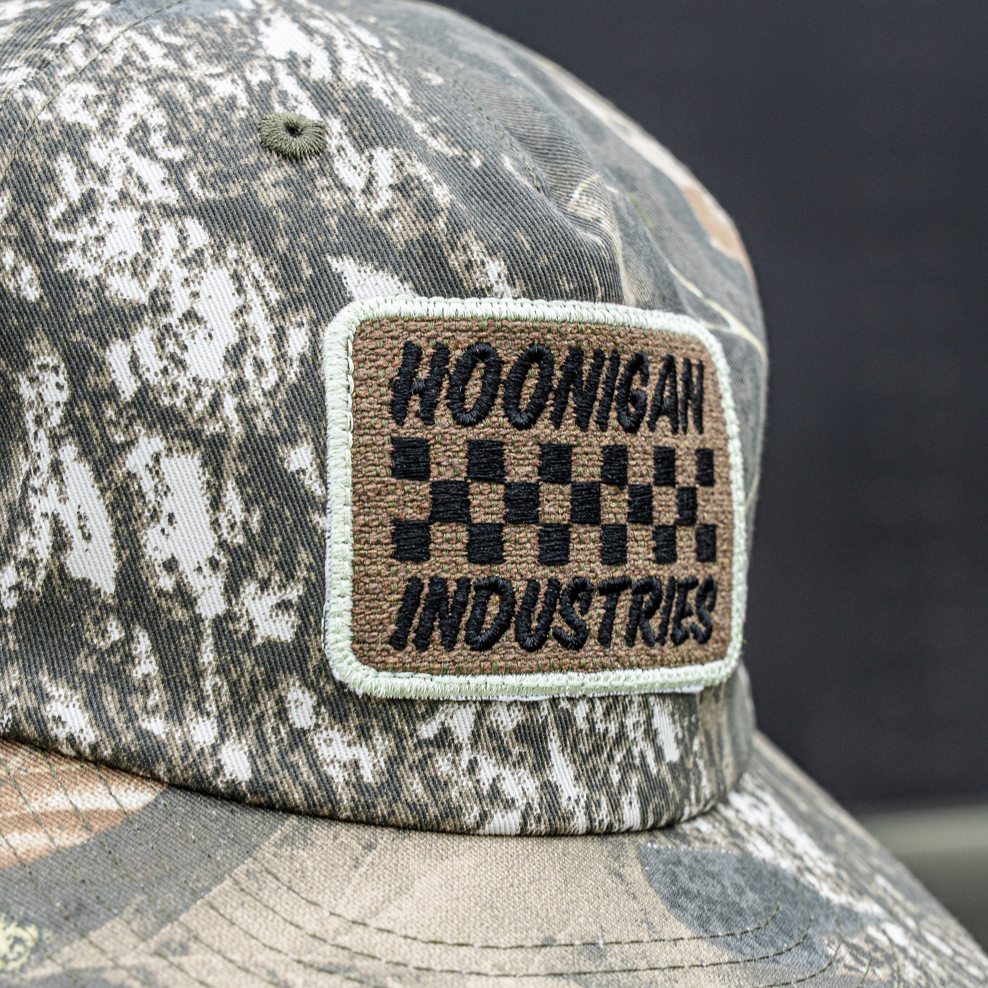 Hoonigan SPRINT unstructured snapback hat featuring a camo pattern and embroidered logo patch. Ideal for motorsport fans.