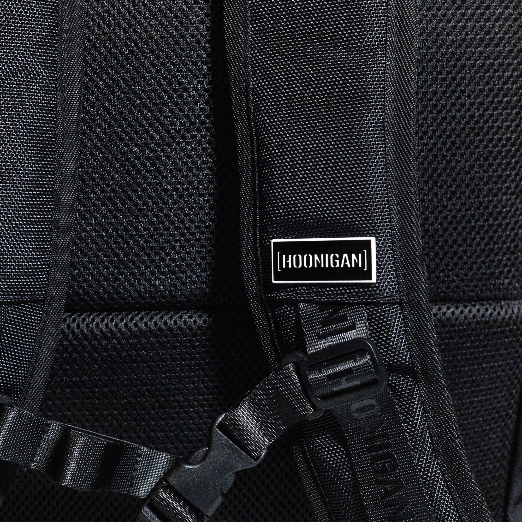 Hoonigan METAL BAR Backpack featuring a sleek black design with a front mesh pocket and adjustable straps.