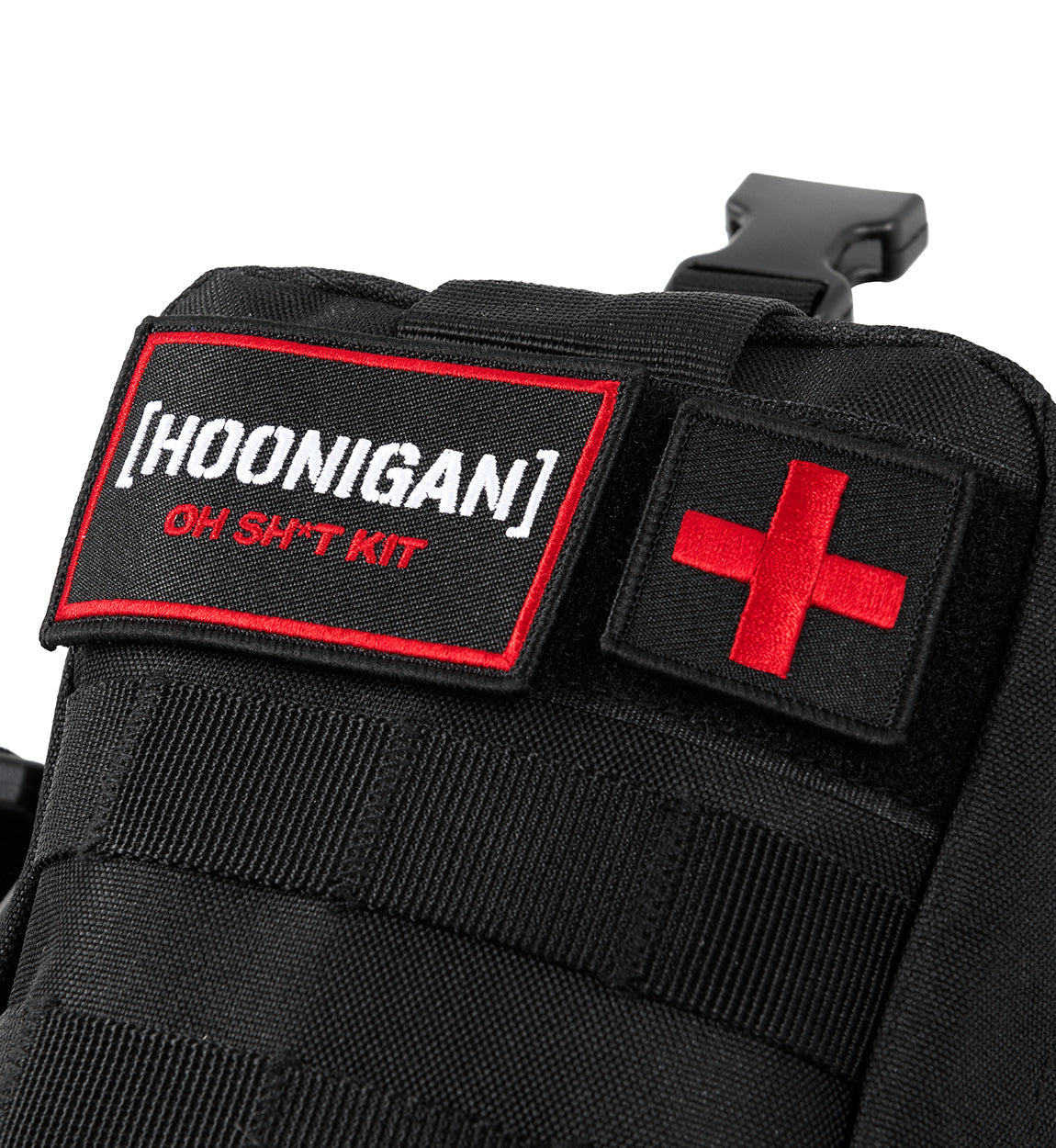 Close-up of the Hoonigan OH SH*T Safety Kit with black fabric, red cross patch, and embroidered label on a vehicle safety bag.