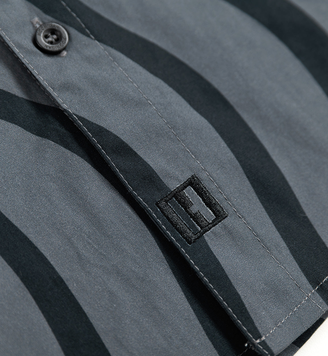 Hoonigan ESSES Woven Short Sleeve Button-up Shirt in black and grey, featuring a sleek design with a modern fit and button-up collar.