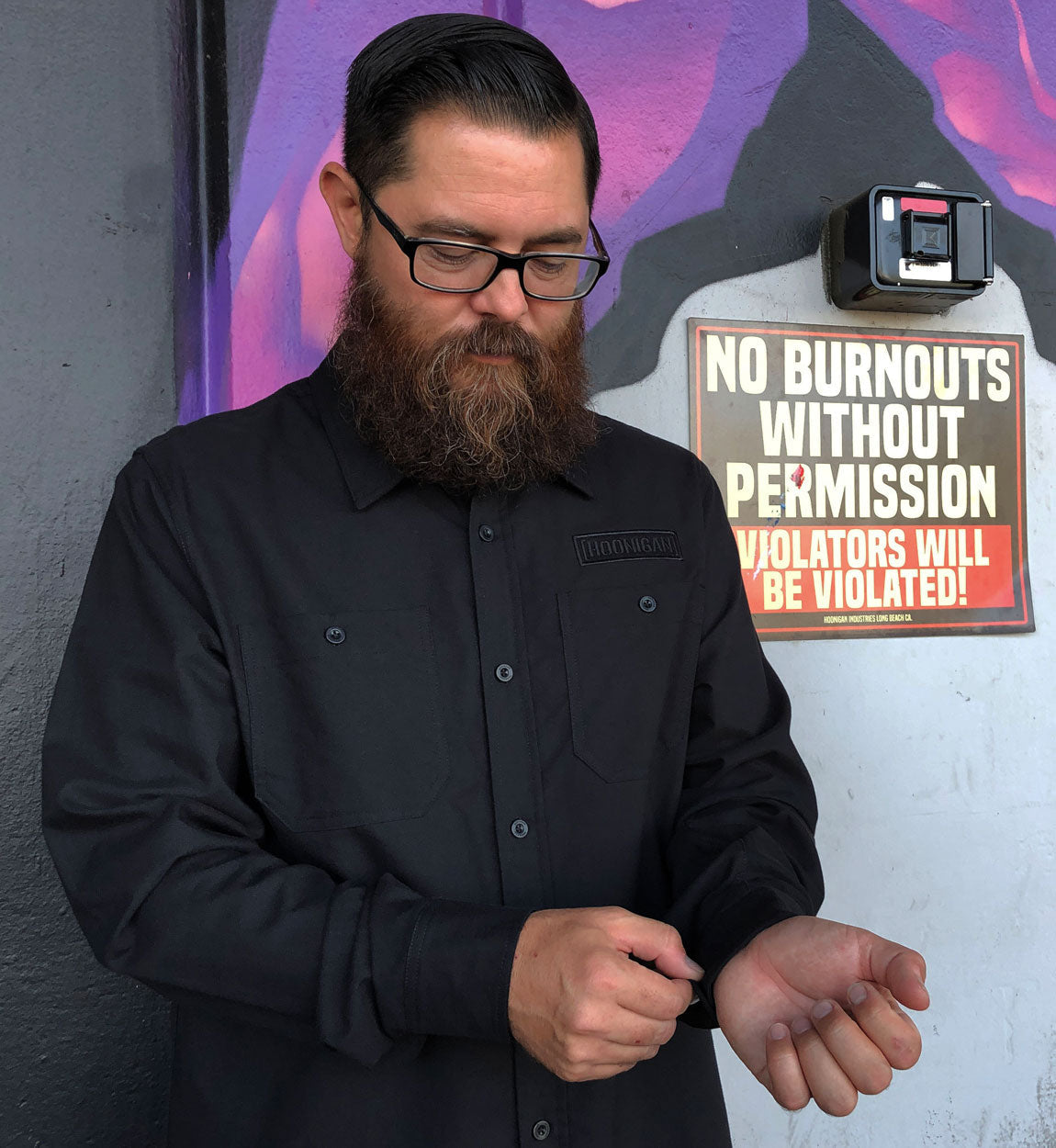 Hoonigan DONUT GARAGE black woven long sleeve button-up shirt displayed on a hanger.