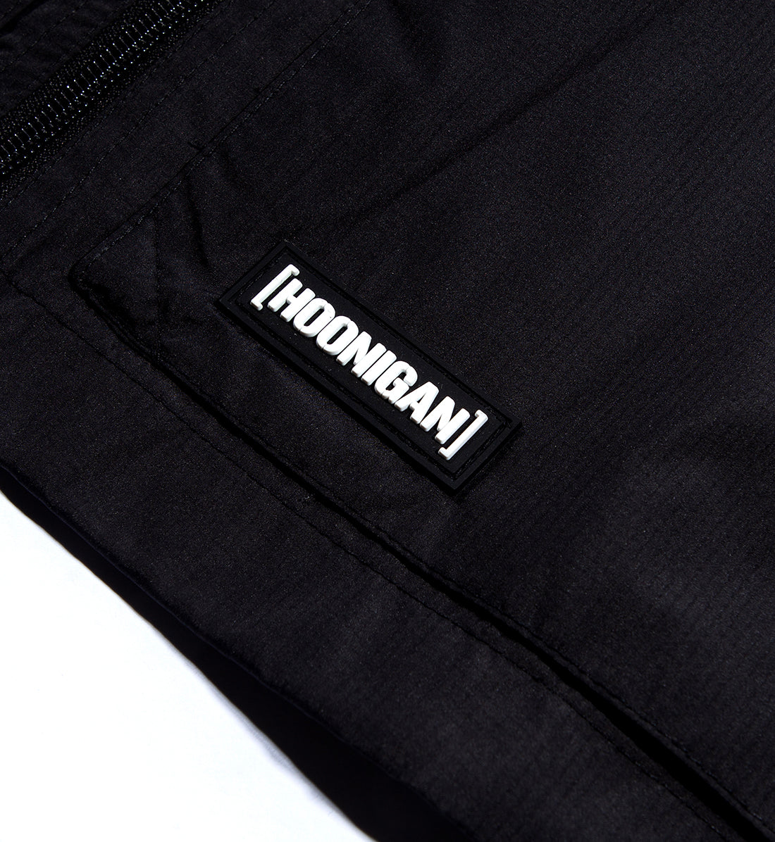 Hoonigan Standard Issue Windbreaker Jacket in black and white, featuring a front pocket and logo detail.
