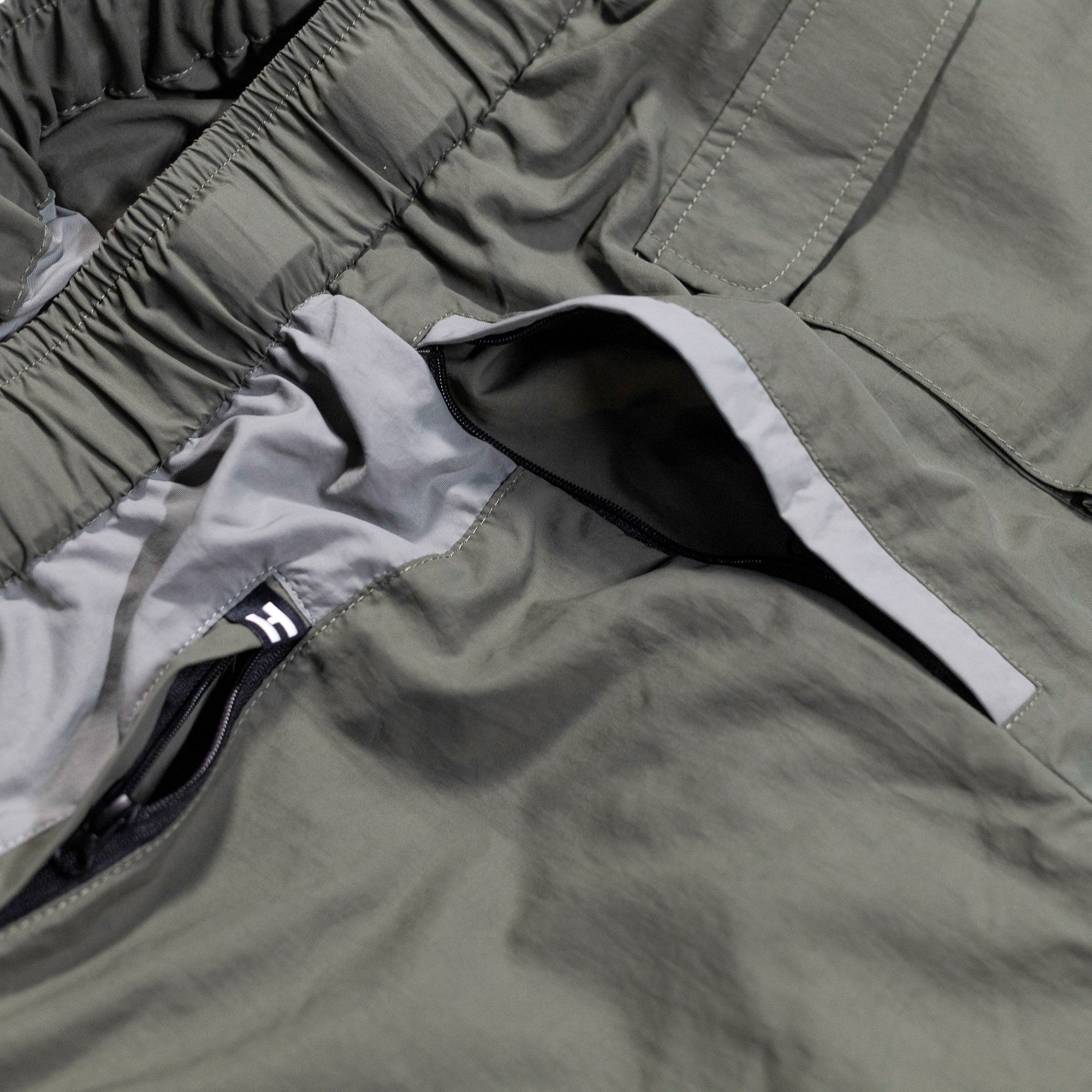 Close-up of Hoonigan H.A.V.O.C. rain-activated cargo shorts showing water-resistant fabric, zippered pocket, and elastic waistband.