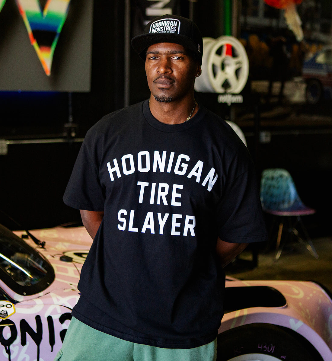 Black Hoonigan TIRE SLAYER short sleeve t-shirt displayed in a lifestyle setting, featuring a large front graphic of the "TIRE SLAYER" logo.