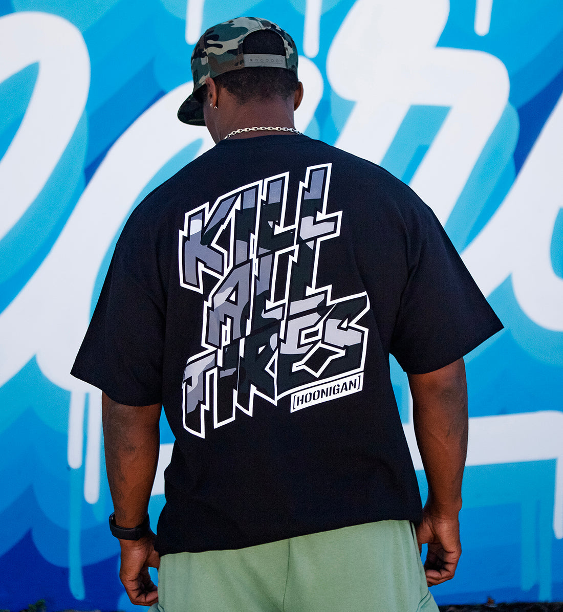 Hoonigan KILL ALL TIRES CAMO short sleeve tee in black with camo graphic, displayed in a lifestyle setting, showcasing its casual fit and stylish design.