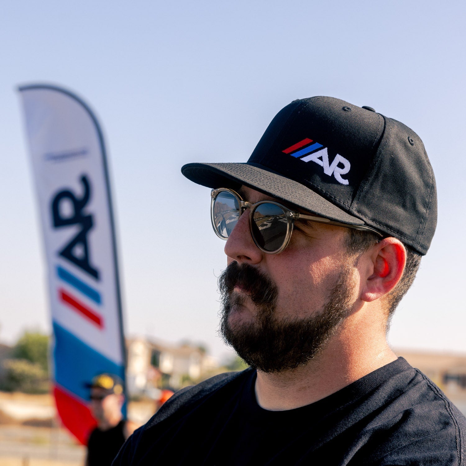 American Racing logo snapback hat in black with white lettering, showcasing a classic design and adjustable strap.
