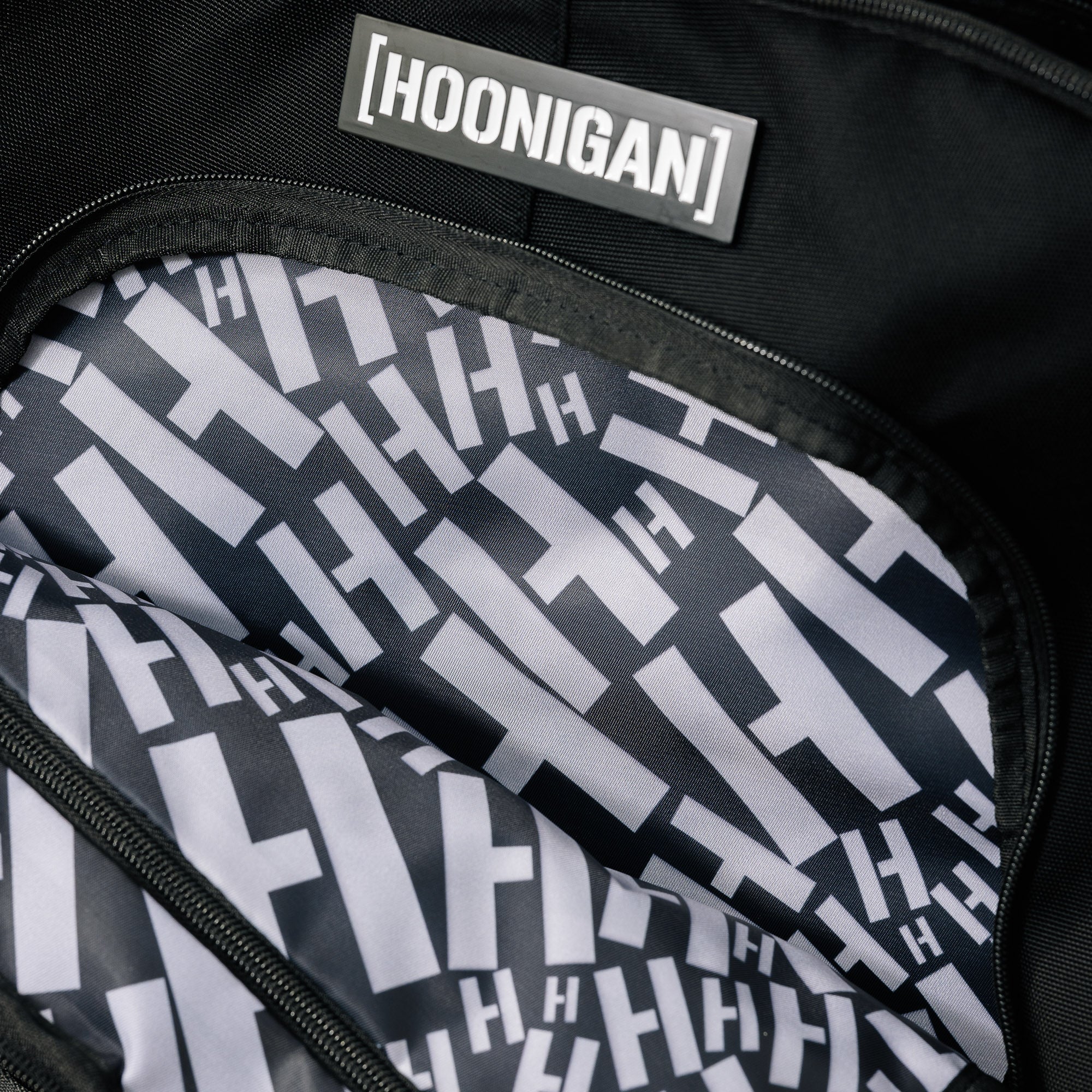 Hoonigan Ratchet Strap Backpack featuring bold branding, adjustable straps, and a durable design, set against a plain background.