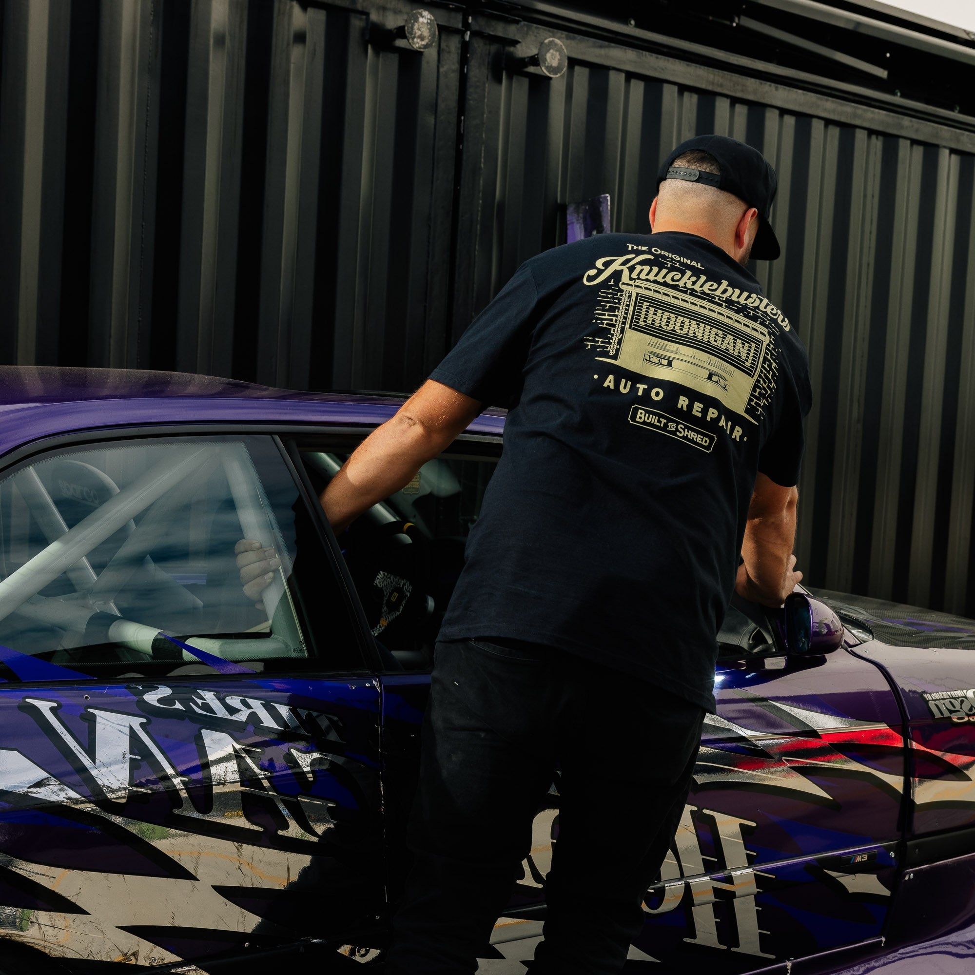 Hoonigan KNUCKLEBUSTERS AUTO REPAIR short sleeve tee featuring a vintage-inspired graphic and bold logo design on a dark shirt.