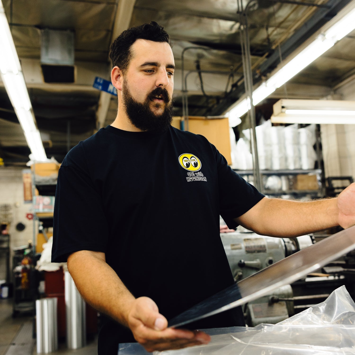 Hoonigan x Mooneyes 'GO WITH HOON' short sleeve tee featuring bold graphic design and logo accents on a black fabric background.