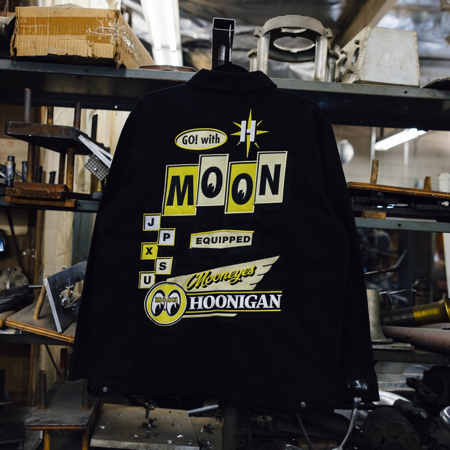 Hoonigan x Mooneyes MOON MOTEL Jacket, featuring a retro design with vibrant graphics and a stylish zip-up front, set against a plain background.