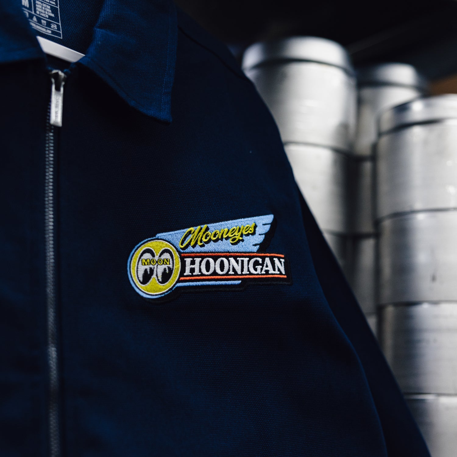 Hoonigan x Mooneyes MOON MOTEL Jacket featuring a black exterior, colorful embroidered logos, and retro motel design elements.