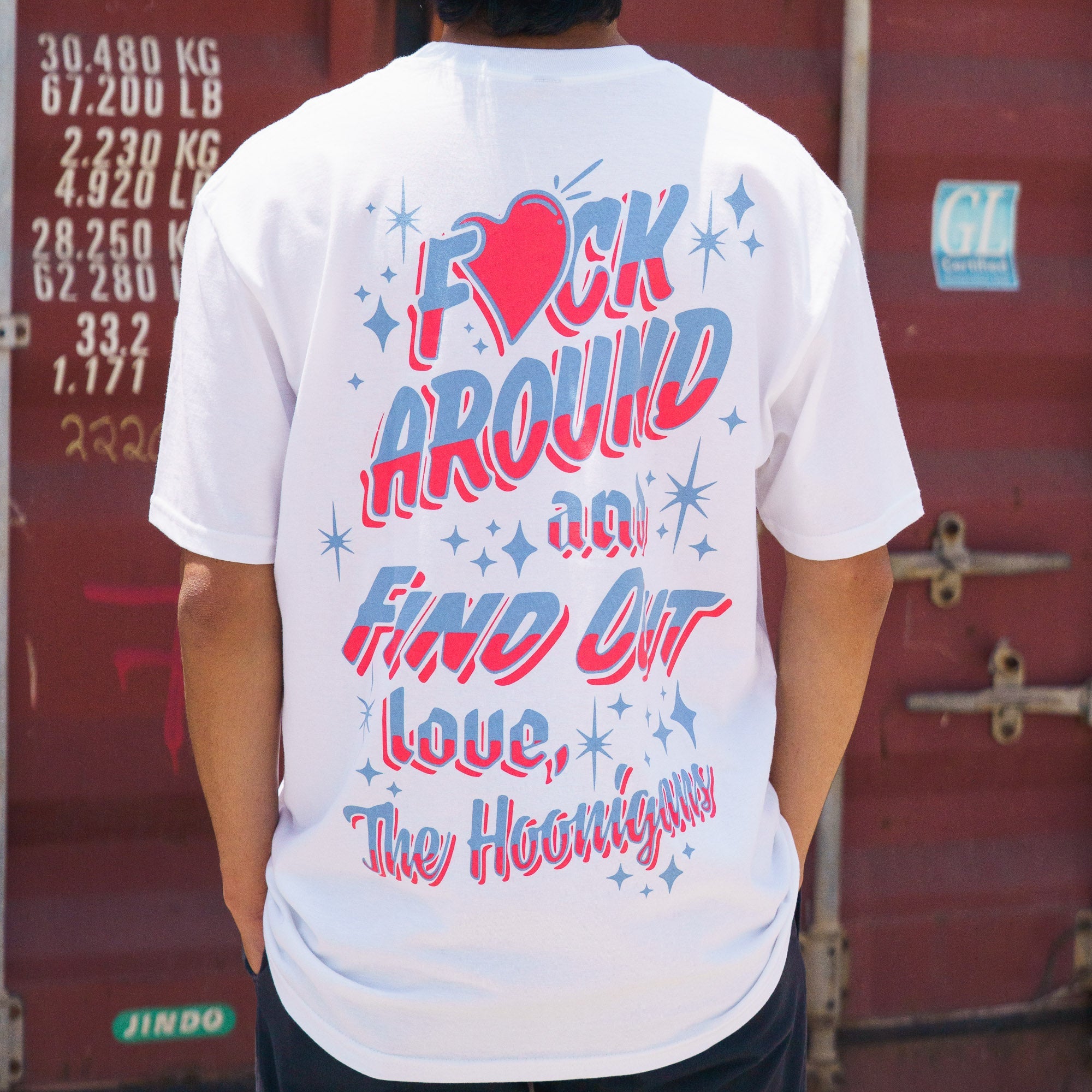 Back view of a white Hoonigan FIND OUT V2 short sleeve tee with colorful, stylized text and star graphics.