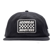 Black unstructured snapback hat featuring a checkerboard patch with "Hoonigan Industries" embroidered on the front.