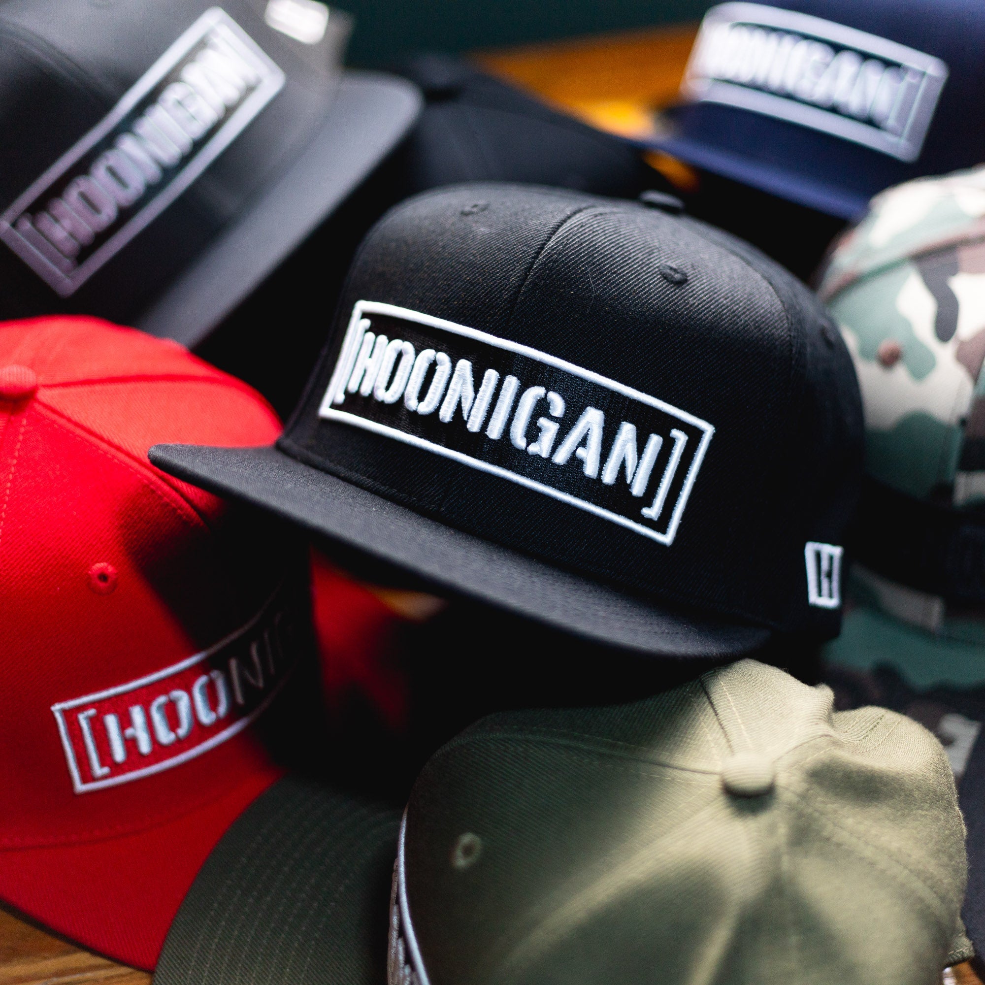 Hoonigan CENSOR BAR Snapback Hat displayed among various colors and styles, showcasing automotive lifestyle apparel.