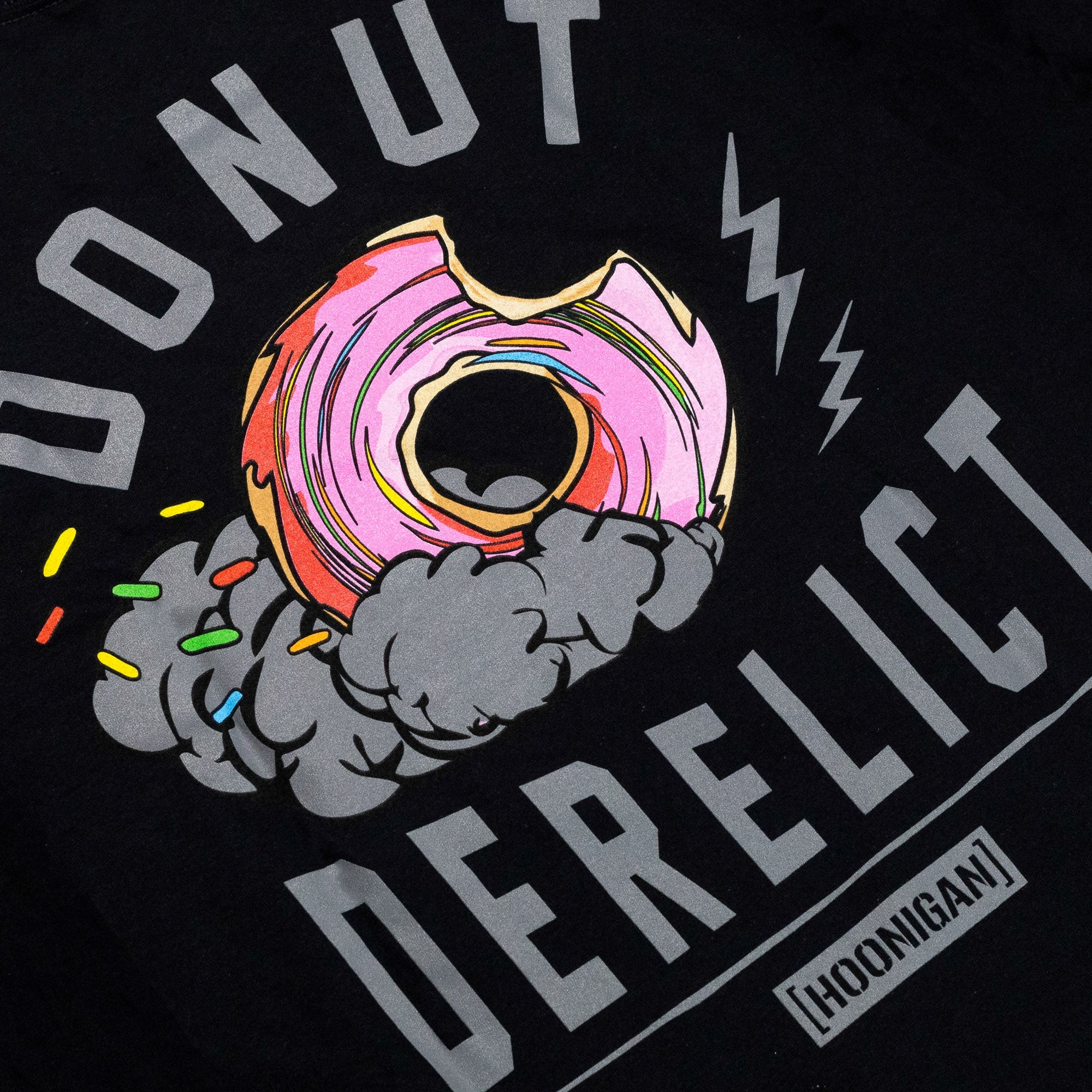 Black short sleeve t-shirt featuring a colorful donut graphic with smoke and the text "DONUT DERELICT" for car culture enthusiasts.