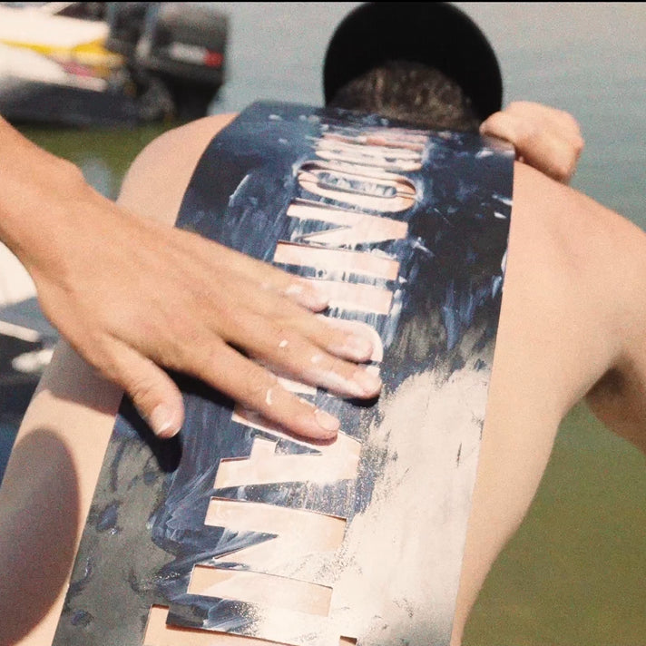 A person applying paint to a HOONIGAN stencil on their back, showcasing the bold design and creative process.