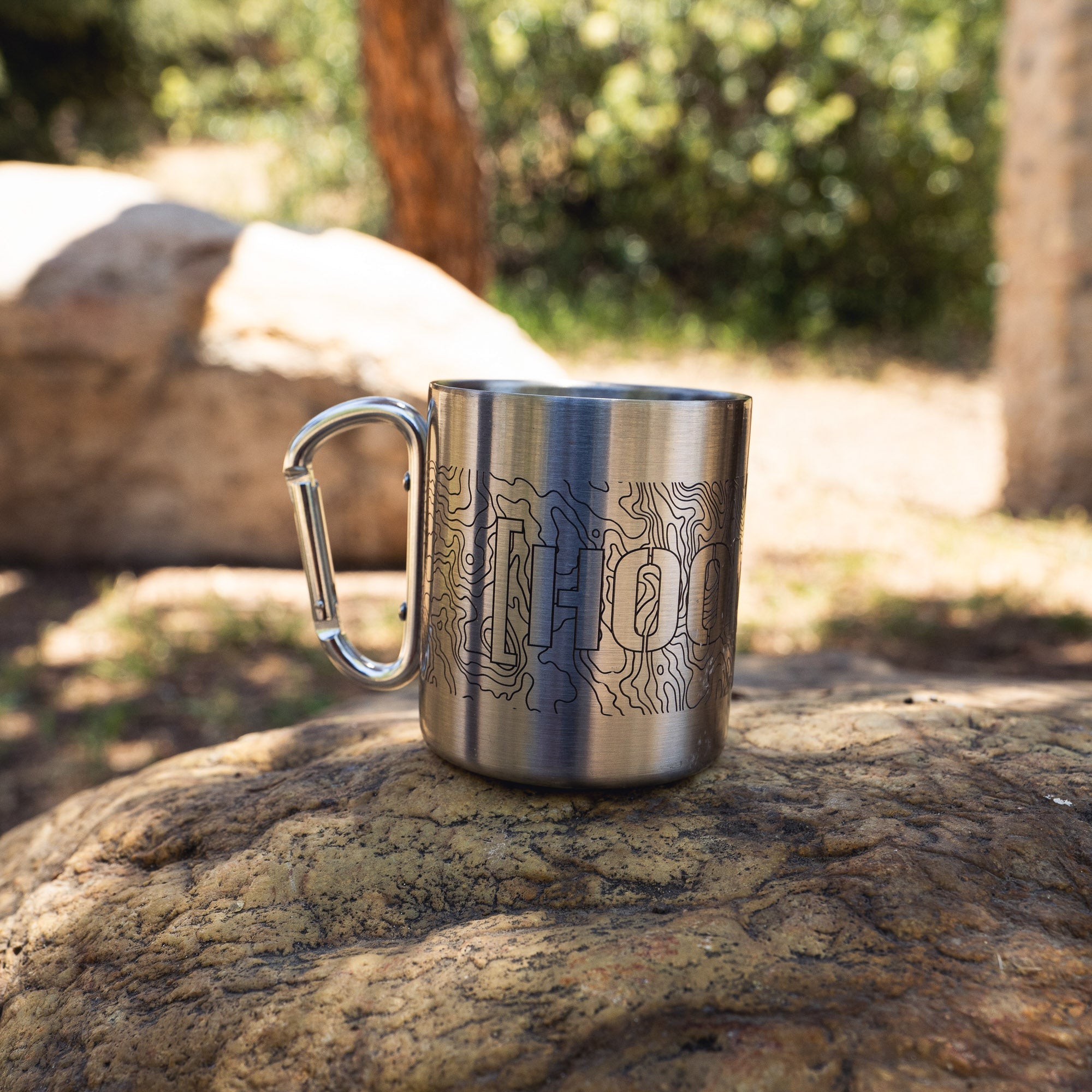 Stainless steel mug with a carabiner handle featuring topographic map design and the word "CENSBOR" engraved on the surface.