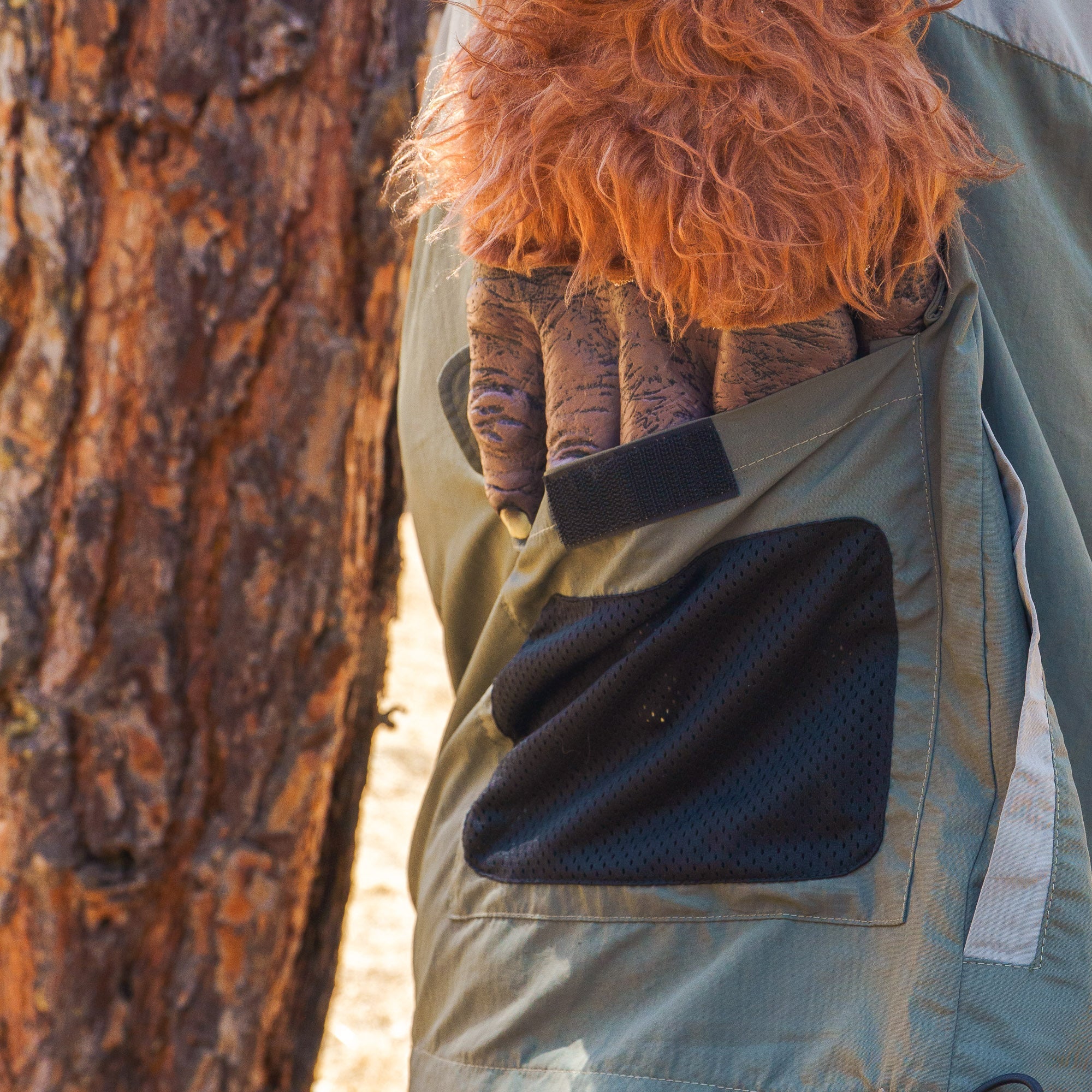 Close-up of Hoonigan H.A.V.O.C. rain-activated cargo shorts with a black mesh pocket, worn outdoors near a tree.