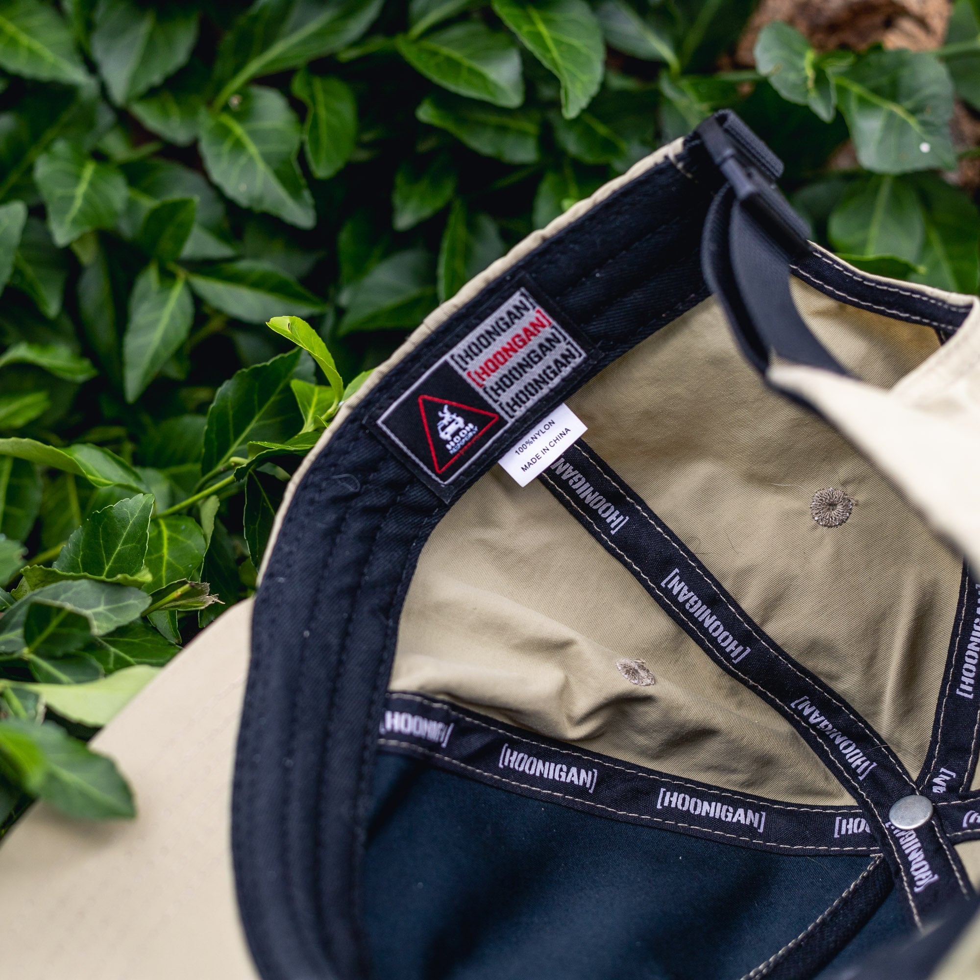 Close-up of the interior of a Hoonigan H.A.V.O.C. unstructured strapback hat with black and beige fabric, and branded inner lining.