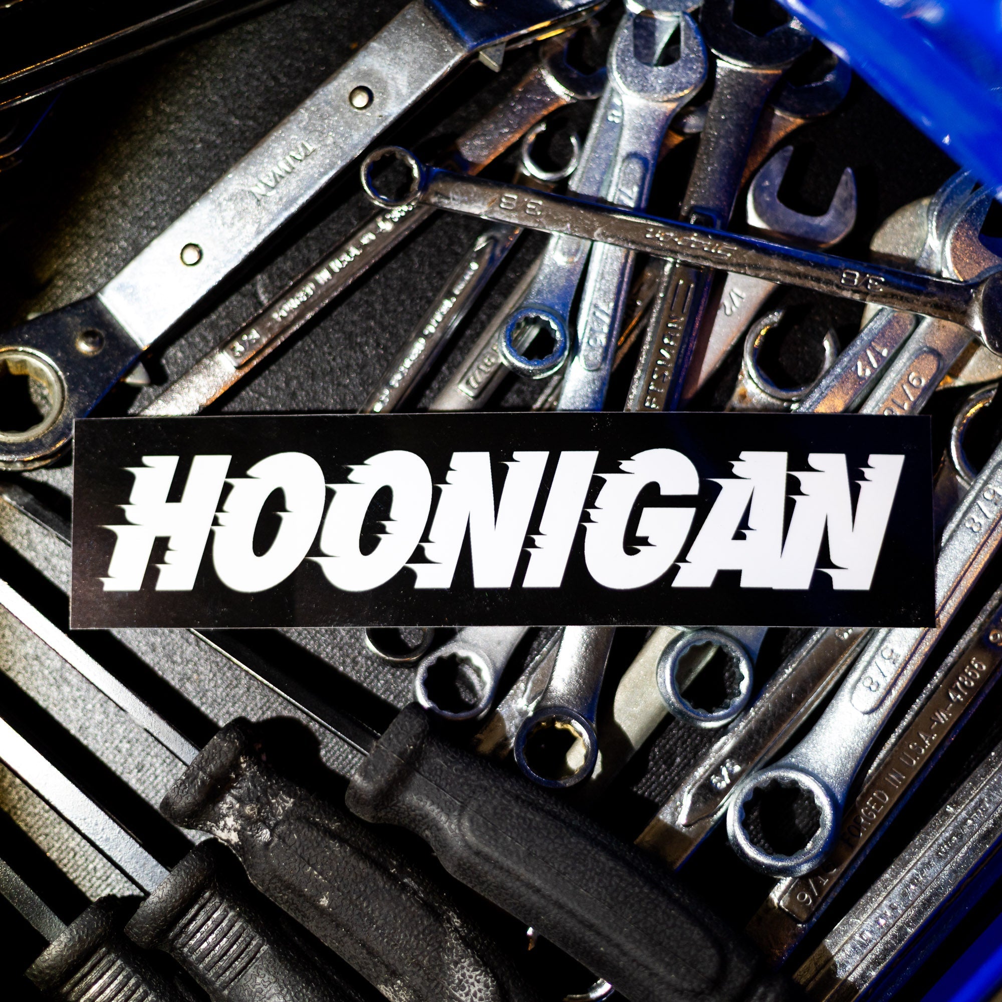 Hoonigan Victory Lap sticker on a background of automotive tools, showcasing a bold and dynamic design.