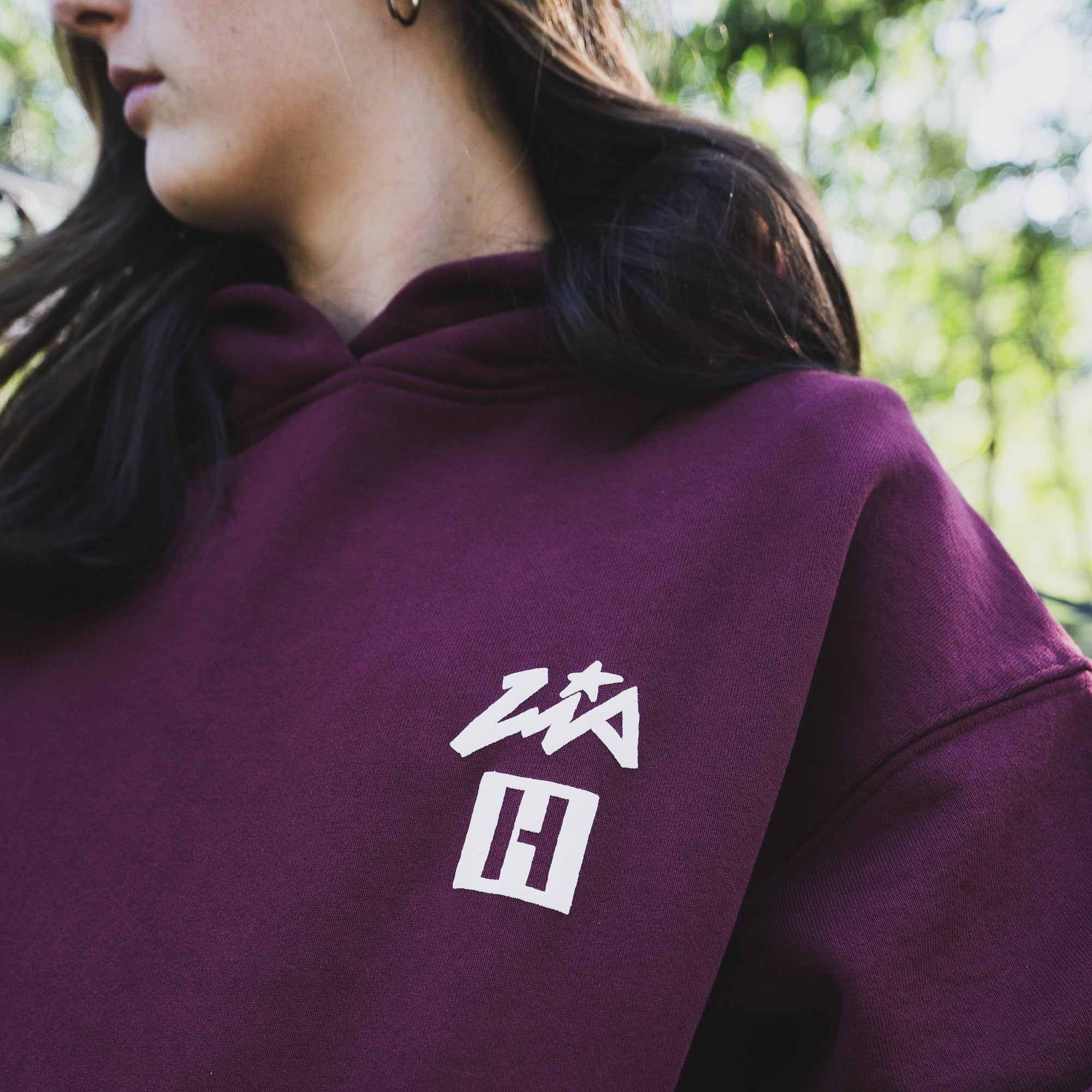 Model wearing a maroon Hoonigan x Lia Block UR STAR pullover hoodie featuring a white logo on the chest.