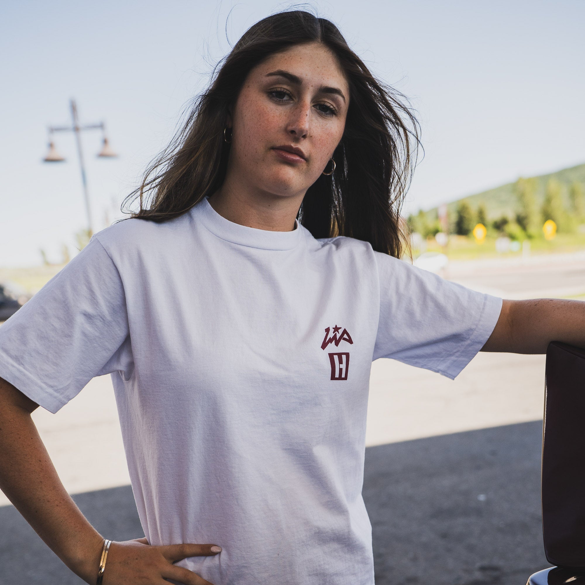 Model wearing a white Hoonigan x Lia Block INNER WORKINGS short sleeve T-shirt, showcasing a stylish automotive lifestyle.