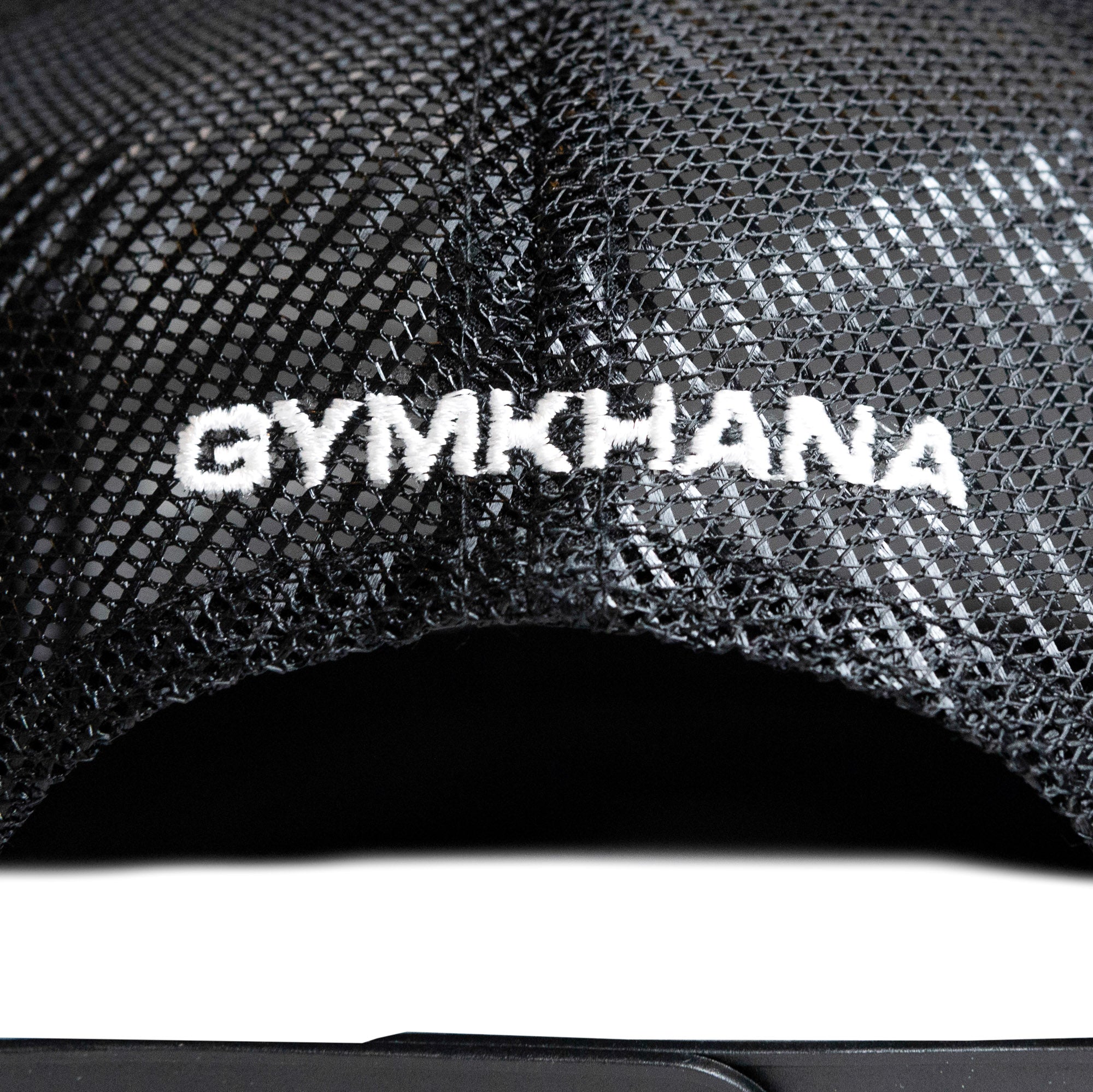 Black trucker strapback hat featuring "GYMKHANA" embroidered in white on the front mesh panel. Ideal for motorsport enthusiasts.