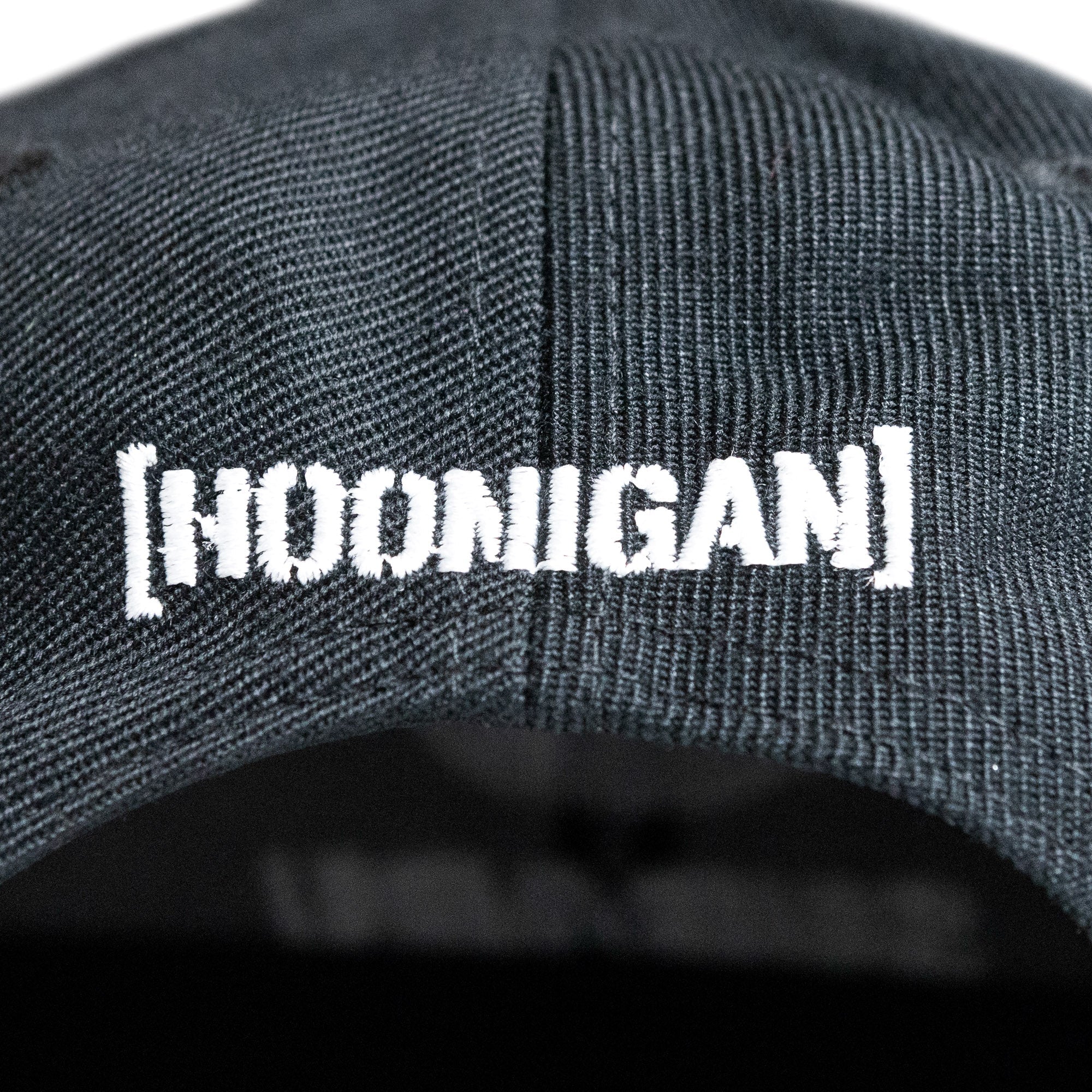 Black snapback hat featuring the Hoonigan logo embroidered in white, perfect for motorsport enthusiasts.