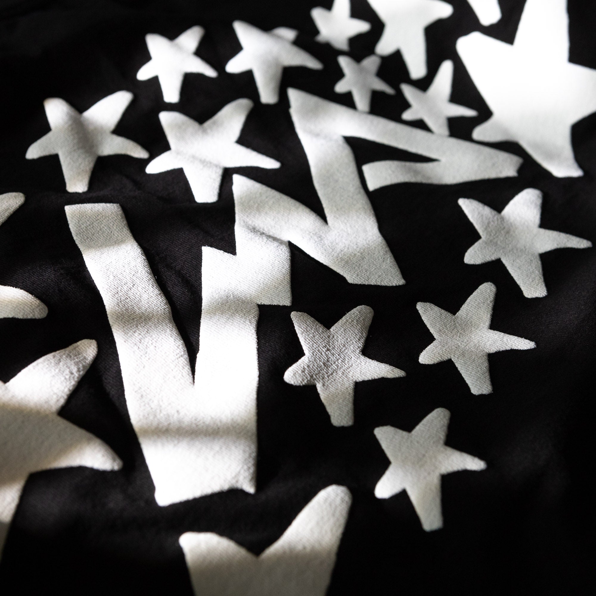 Close-up of the Hoonigan x Lia Block UR STAR Short Sleeve T-Shirt featuring bold white star graphics on a black background.