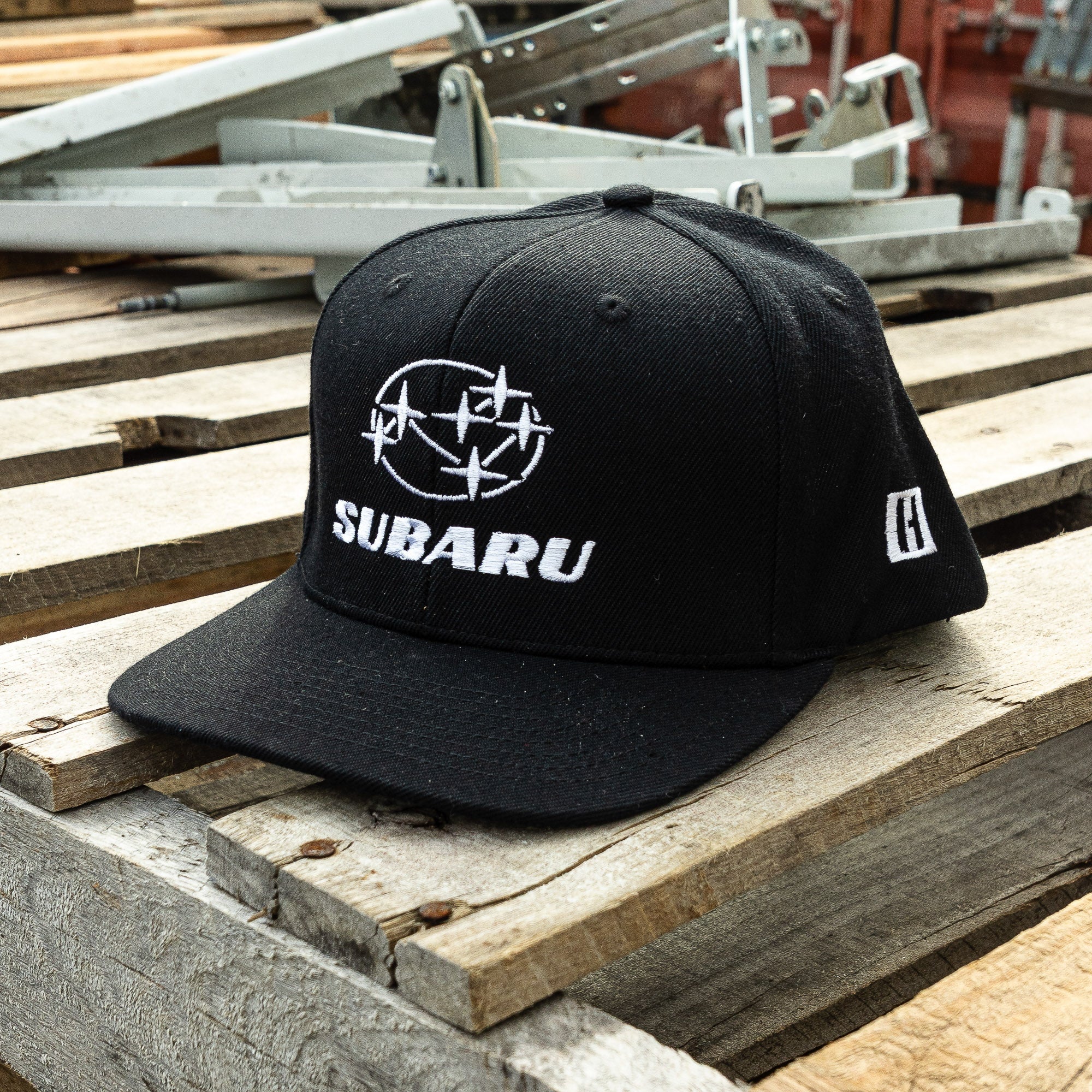 Black snapback hat featuring the Subaru logo and Hoonigan branding, perfect for motorsport enthusiasts and car culture fans.