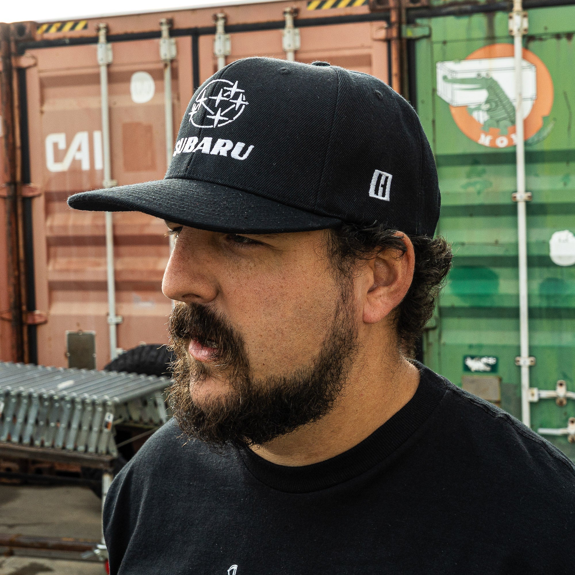 Hoonigan GYMKHANA AUSSIE SHRED SUBARU Snapback Hat worn by a man, featuring a bold Subaru logo and a classic black design.