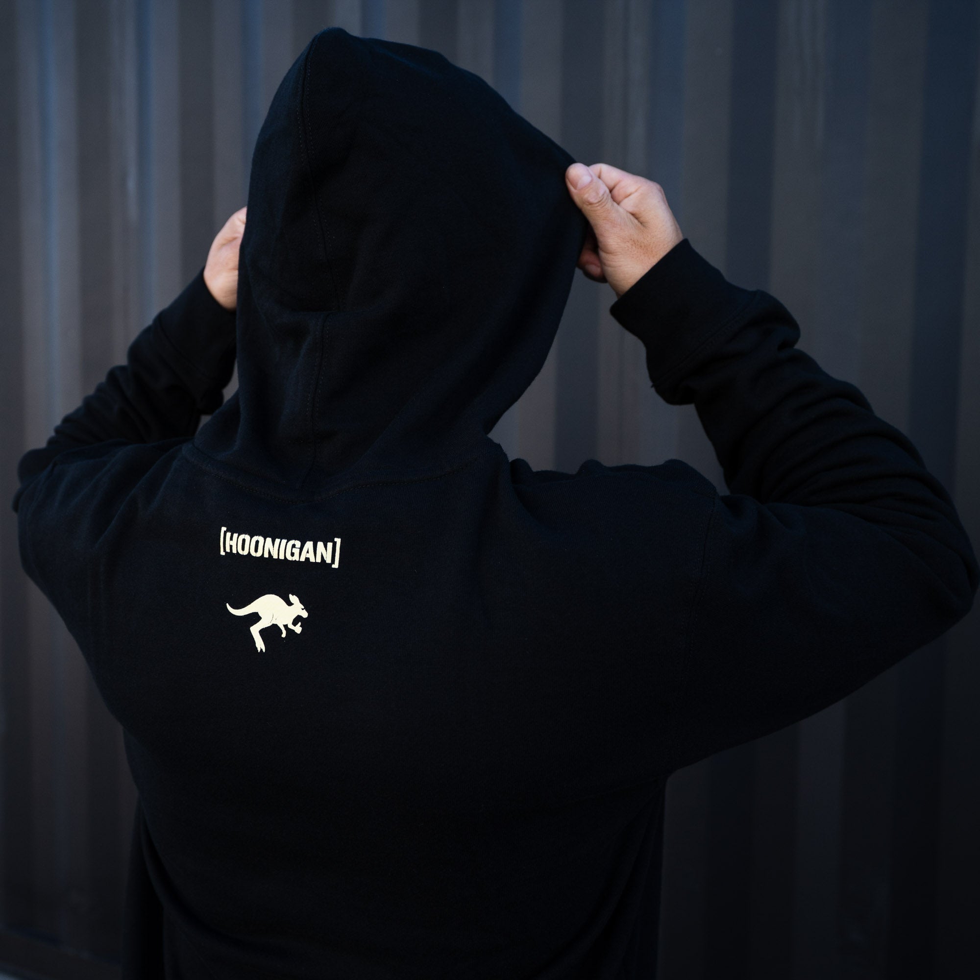 Black pullover hoodie featuring the Hoonigan logo and kangaroo graphic on the back, perfect for motorsport enthusiasts.