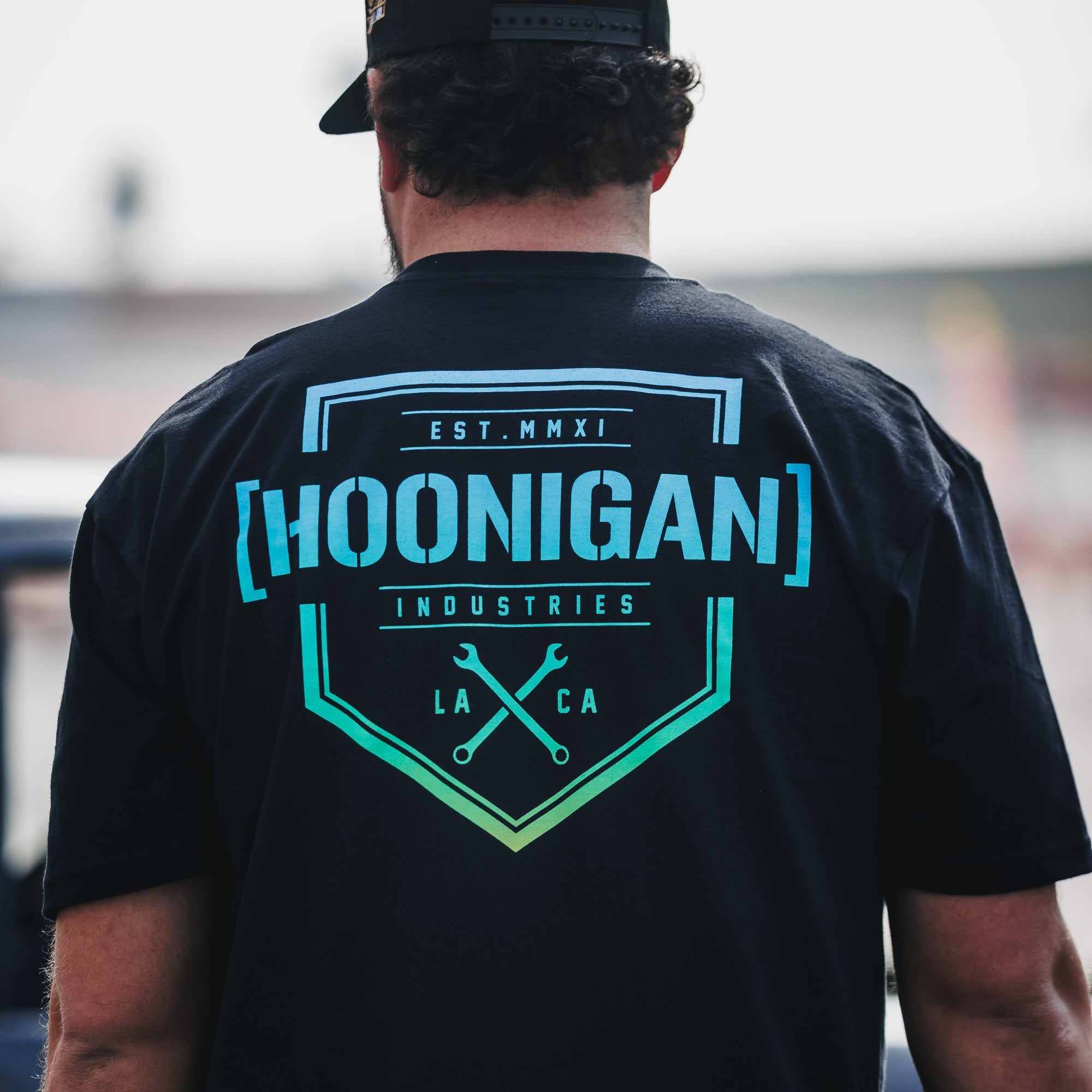 Black short sleeve t-shirt featuring the Hoonigan logo and wrench graphic on the back, designed for motorsport enthusiasts.