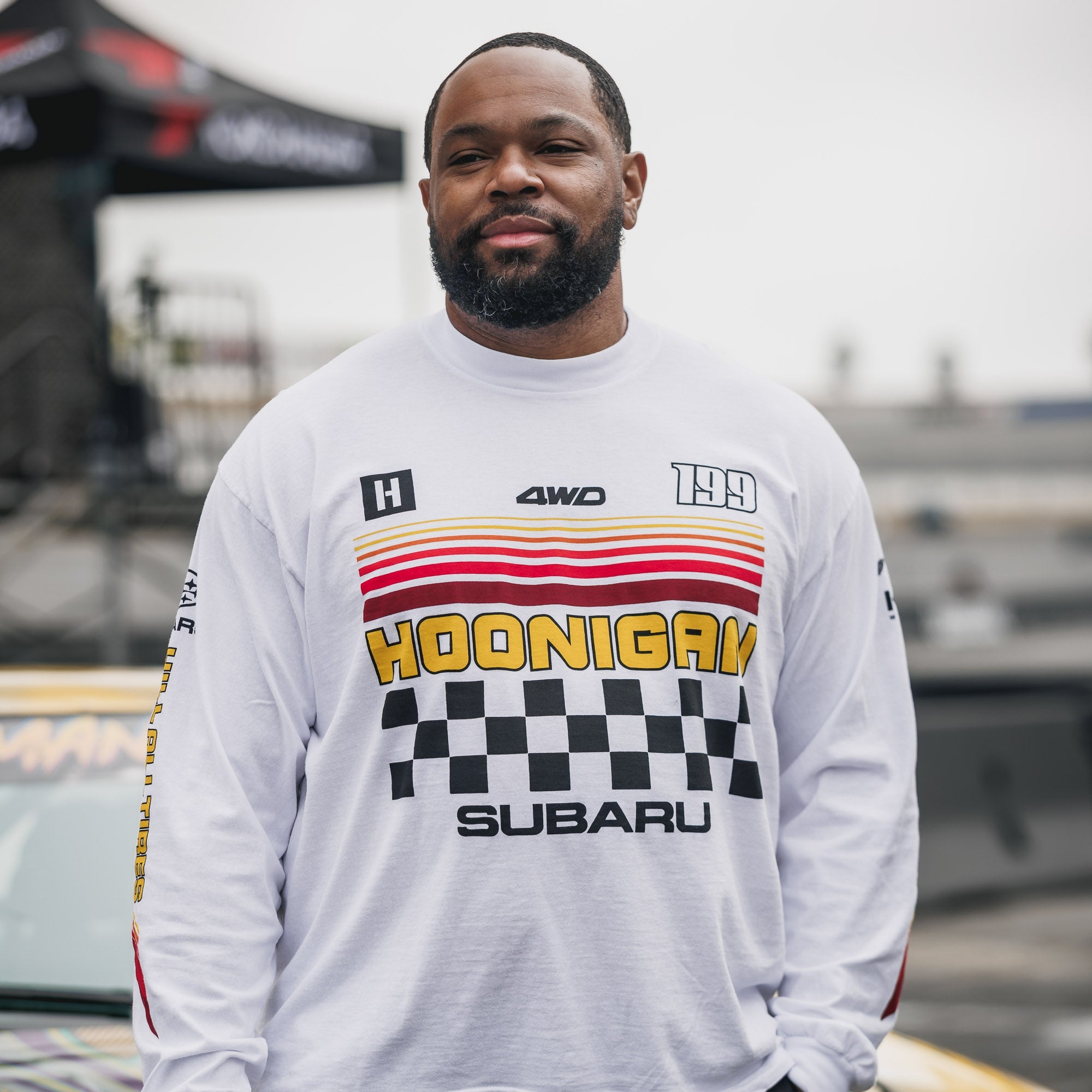 Hoonigan GYMKHANA AUSSIE SHRED Team Long Sleeve T-Shirt displayed on a man, featuring bold graphics and a sporty design.