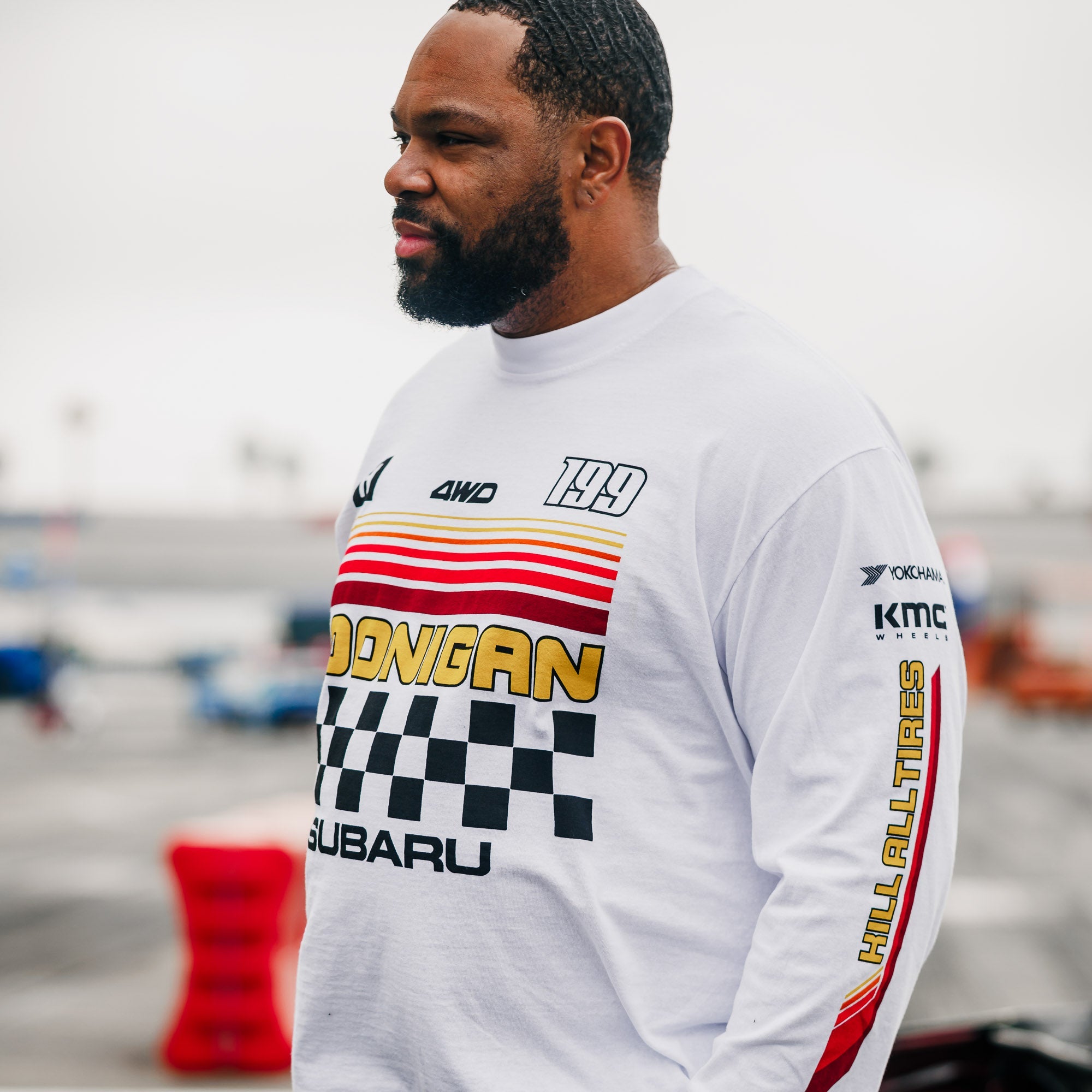Man wearing a Hoonigan GYMKHANA AUSSIE SHRED Team Long Sleeve T-Shirt featuring bold graphics and a racing theme.