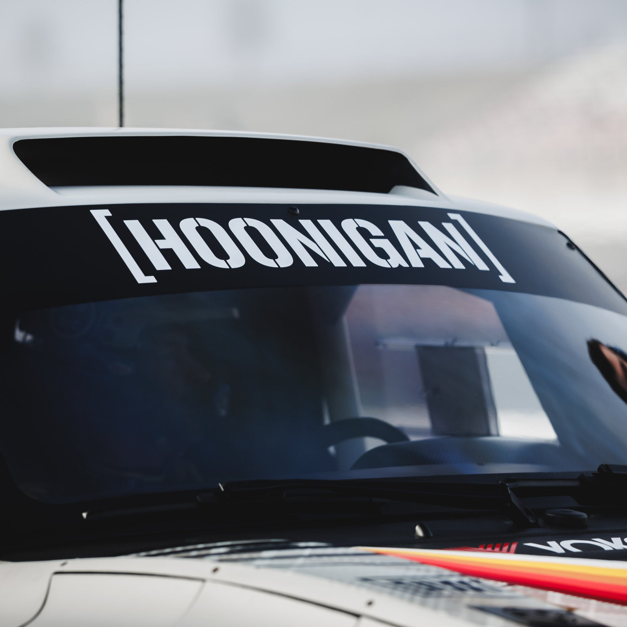 Large die-cut Hoonigan sticker displayed on a car's windshield, showcasing bold lettering and automotive style.
