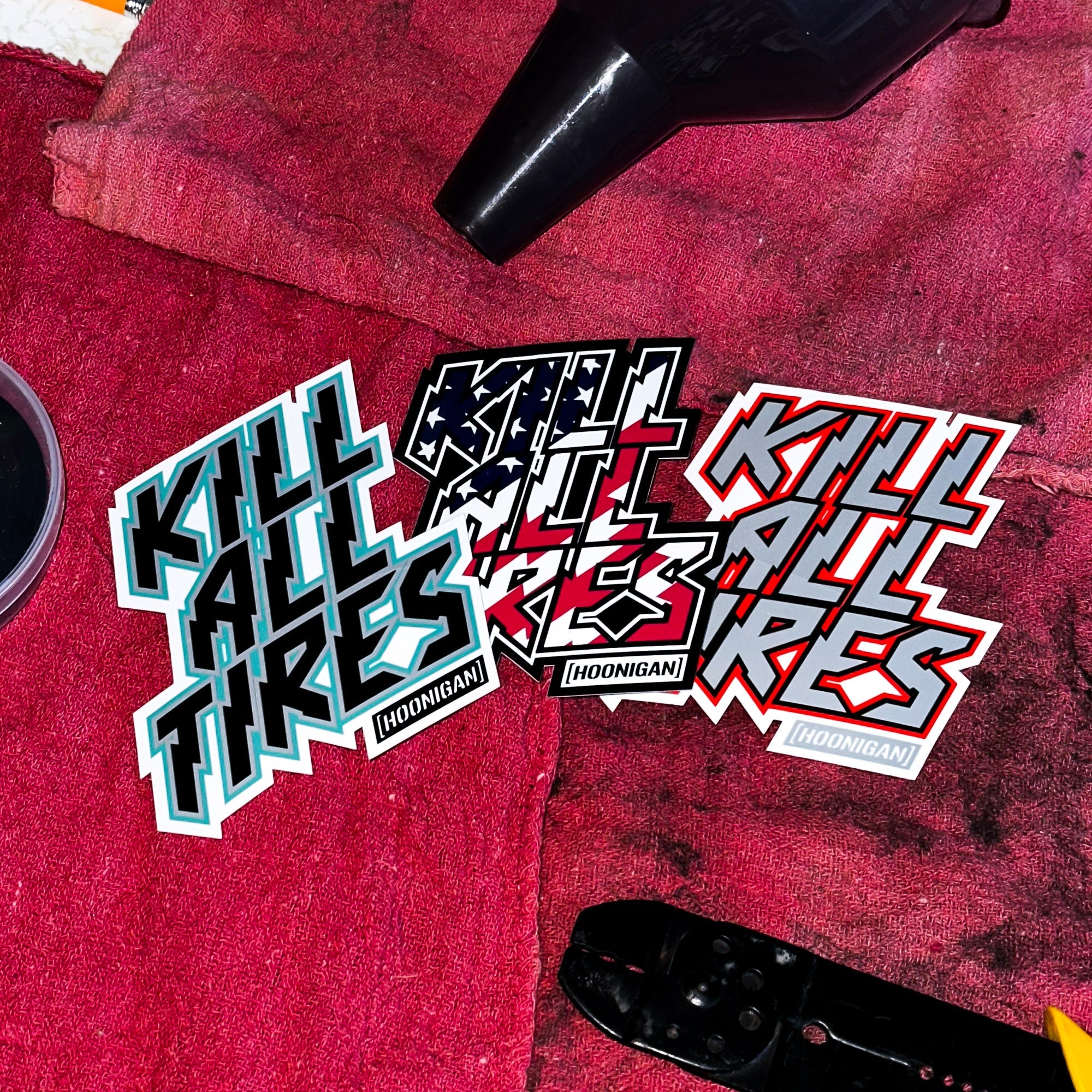 Hoonigan KILL ALL TIRES sticker set featuring bold, colorful designs on a textured red background.