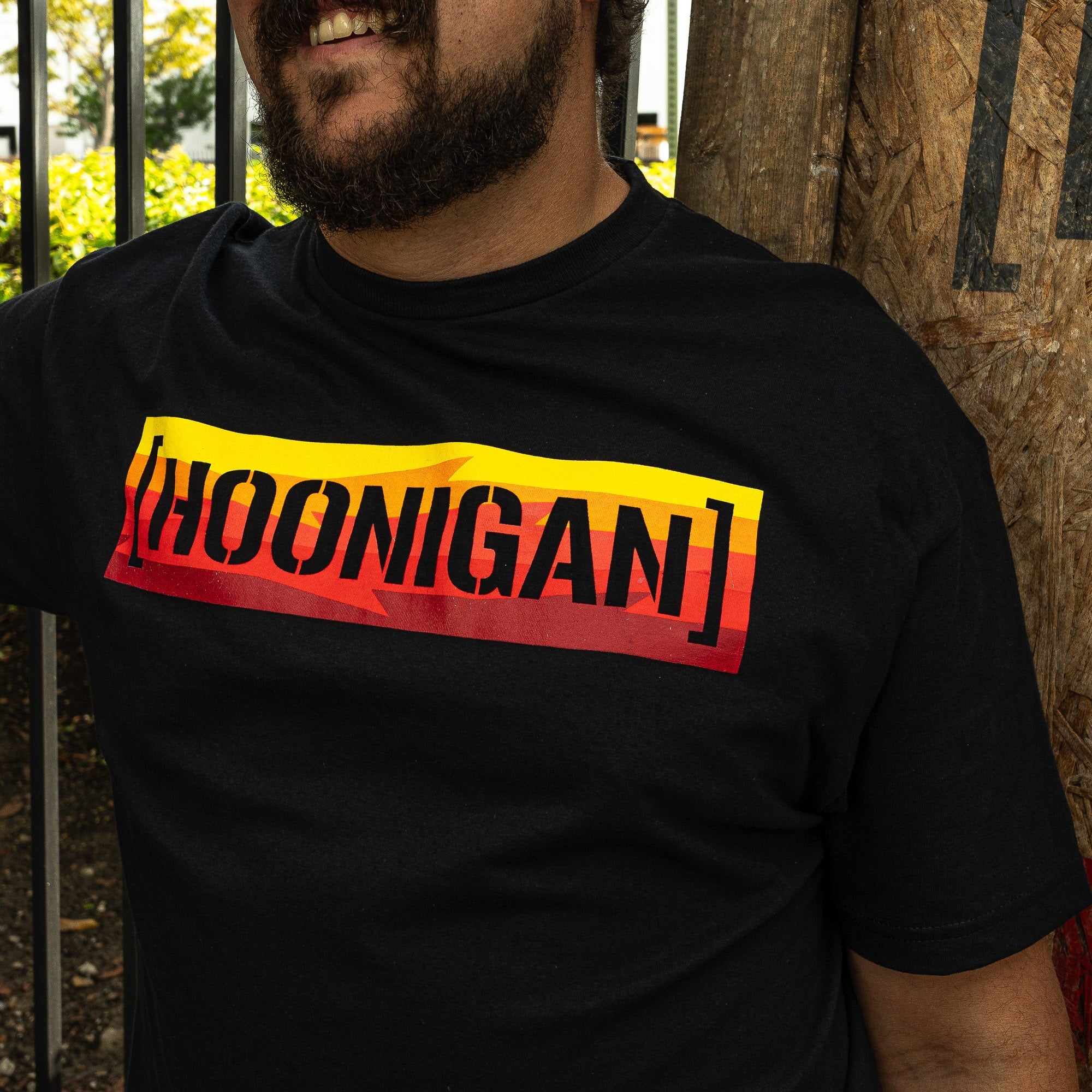 Black short sleeve t-shirt featuring a bold red and yellow Hoonigan logo, perfect for motorsport enthusiasts.