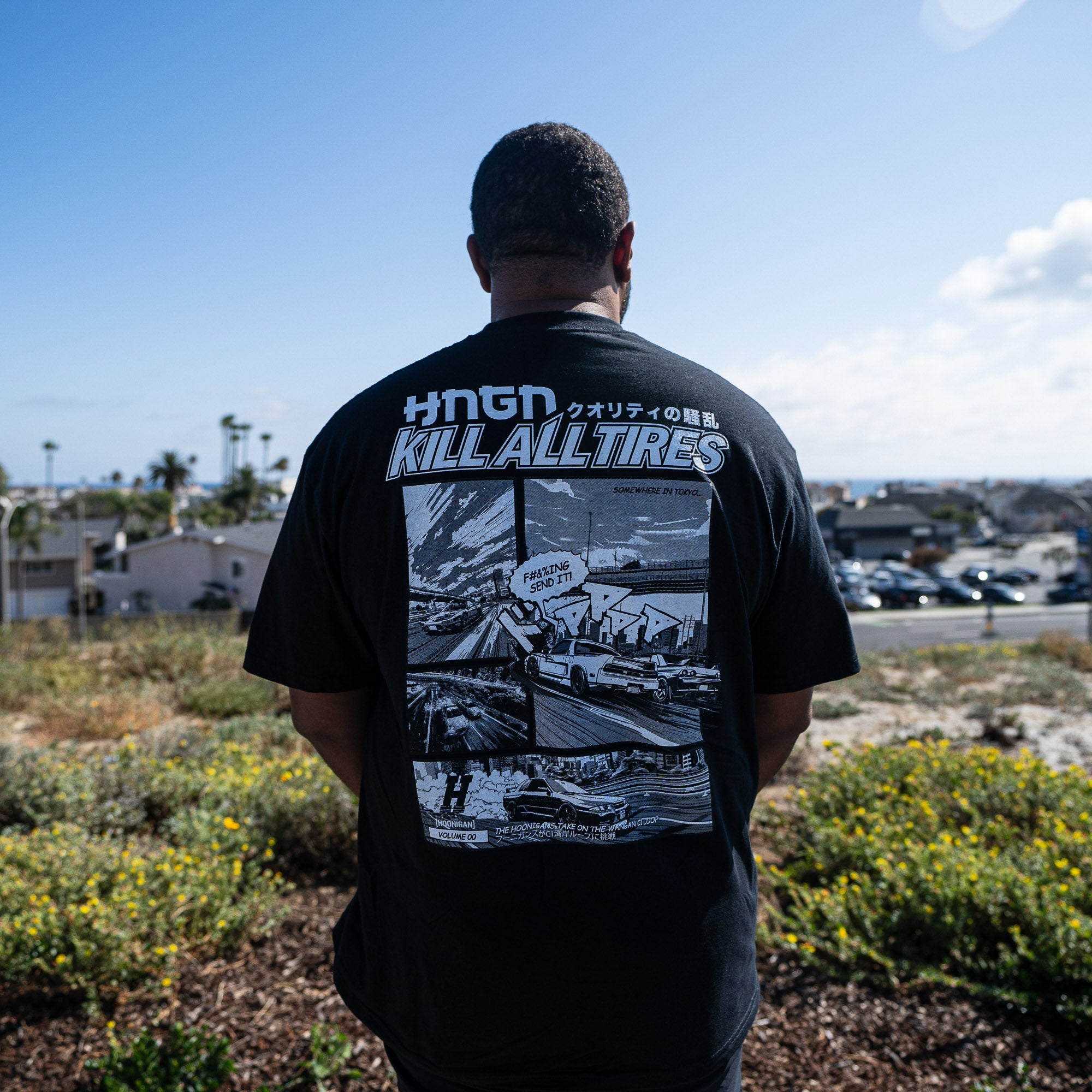 Man wearing Hoonigan WANGAN C1 Short Sleeve Tee, featuring a graphic design with a road scene and the text "KILL ALL TIRES.