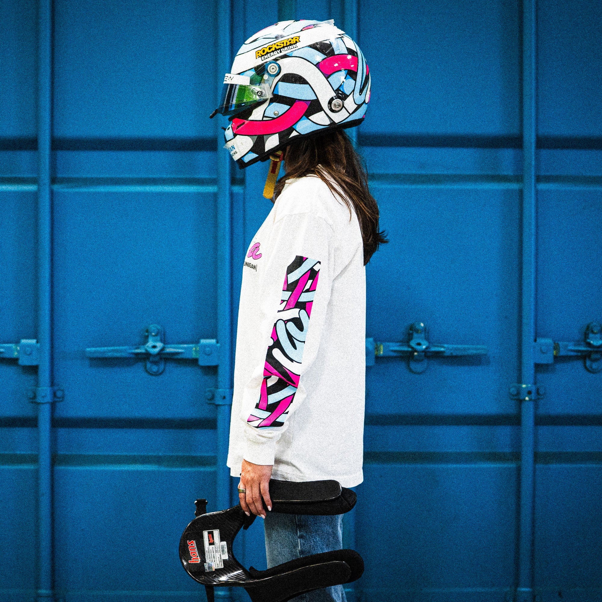 Model wearing Hoonigan x Lia Block SCRIPT Long Sleeve T-Shirt with vibrant sleeve graphics and a colorful helmet.