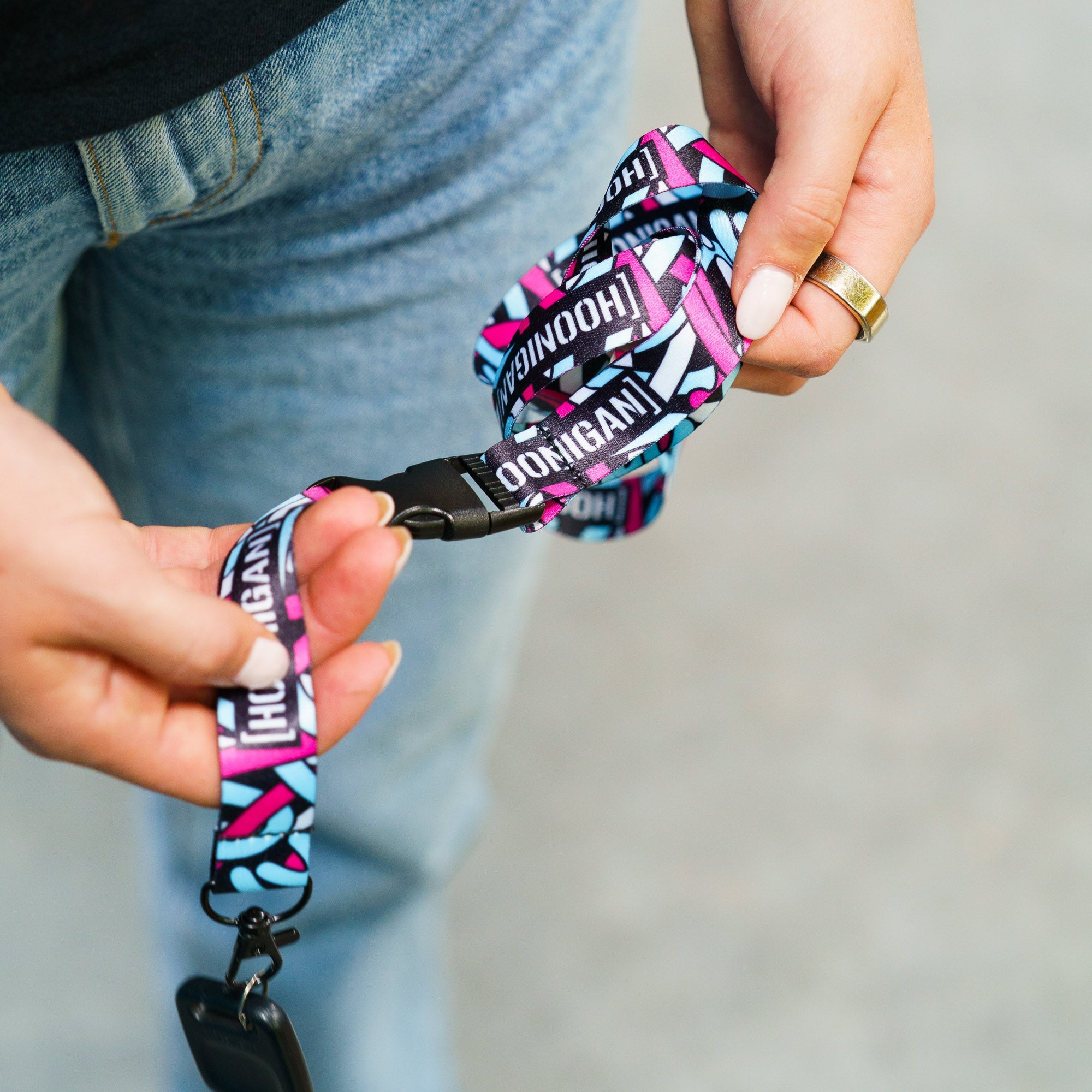 Colorful Hoonigan x Lia Block SCRIPT lanyard held by a person, featuring bold branding and a secure clip for keys or ID.