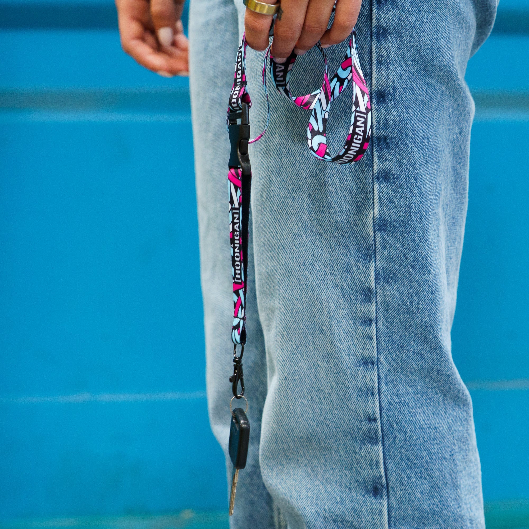 Hoonigan x Lia Block SCRIPT lanyard displayed with keys, featuring a vibrant design against denim jeans.