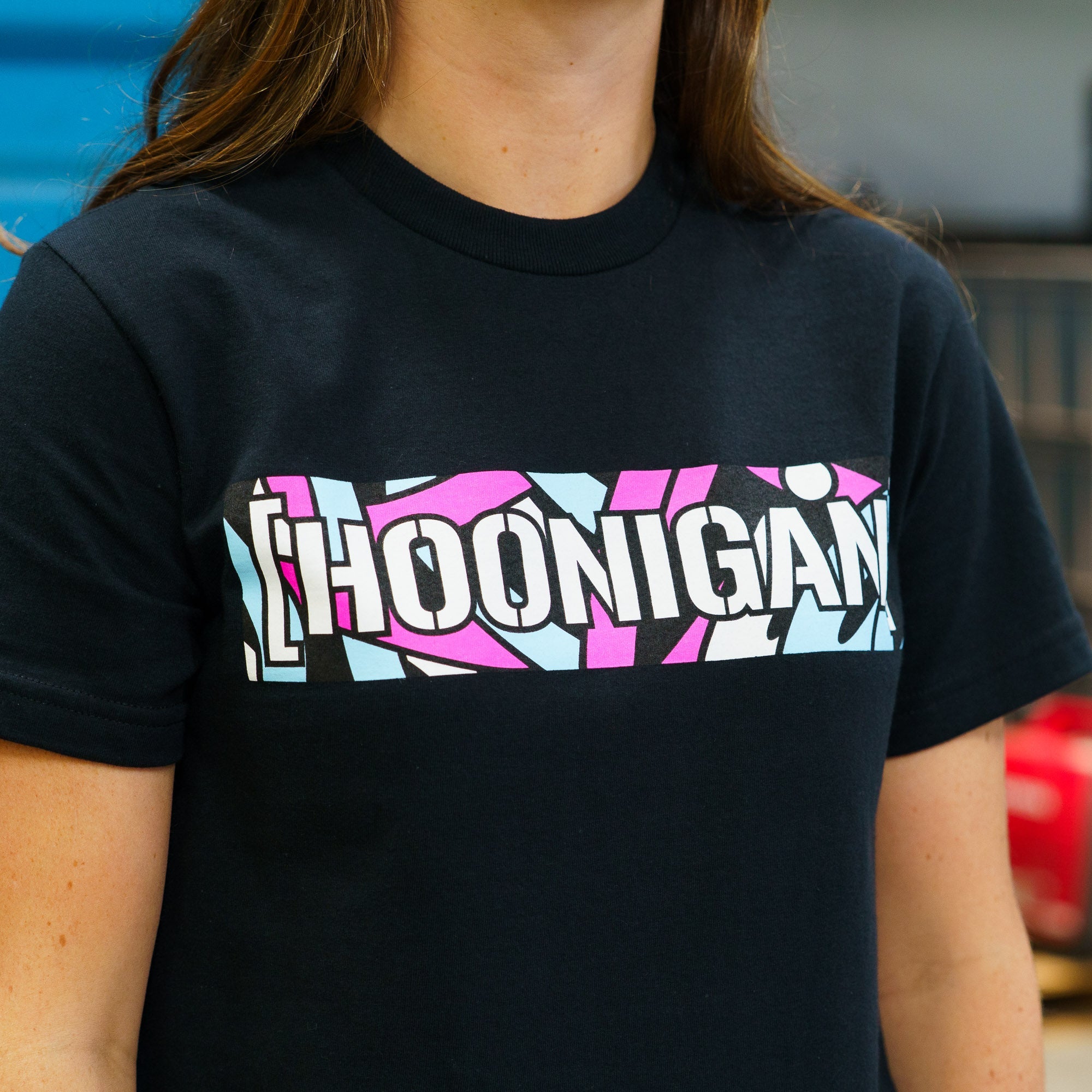 Black short sleeve t-shirt featuring a colorful Hoonigan logo design, perfect for motorsport enthusiasts and car culture fans.