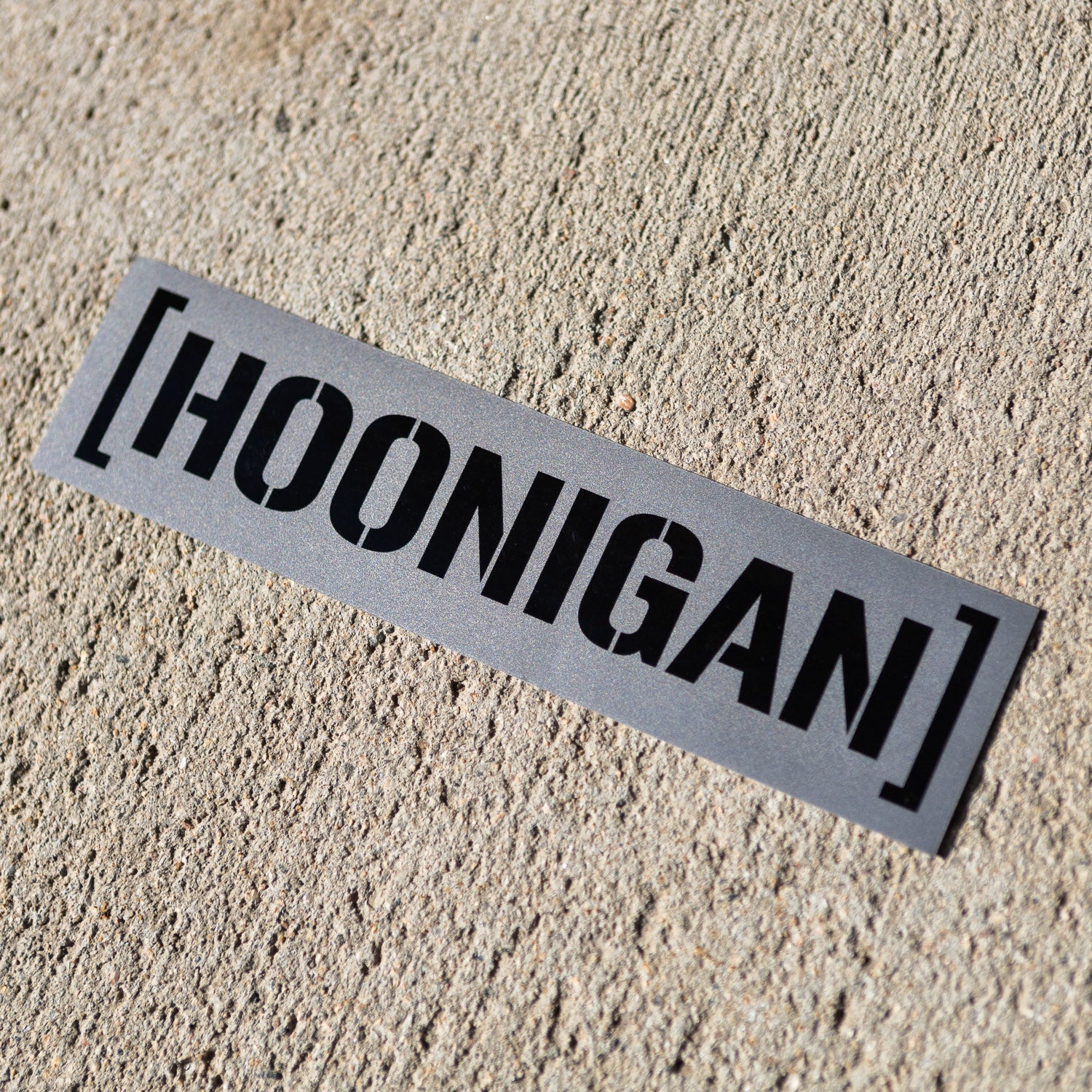 Hoonigan BEAMS CENSOR BAR sticker on a textured surface, showcasing bold black lettering on a silver background.